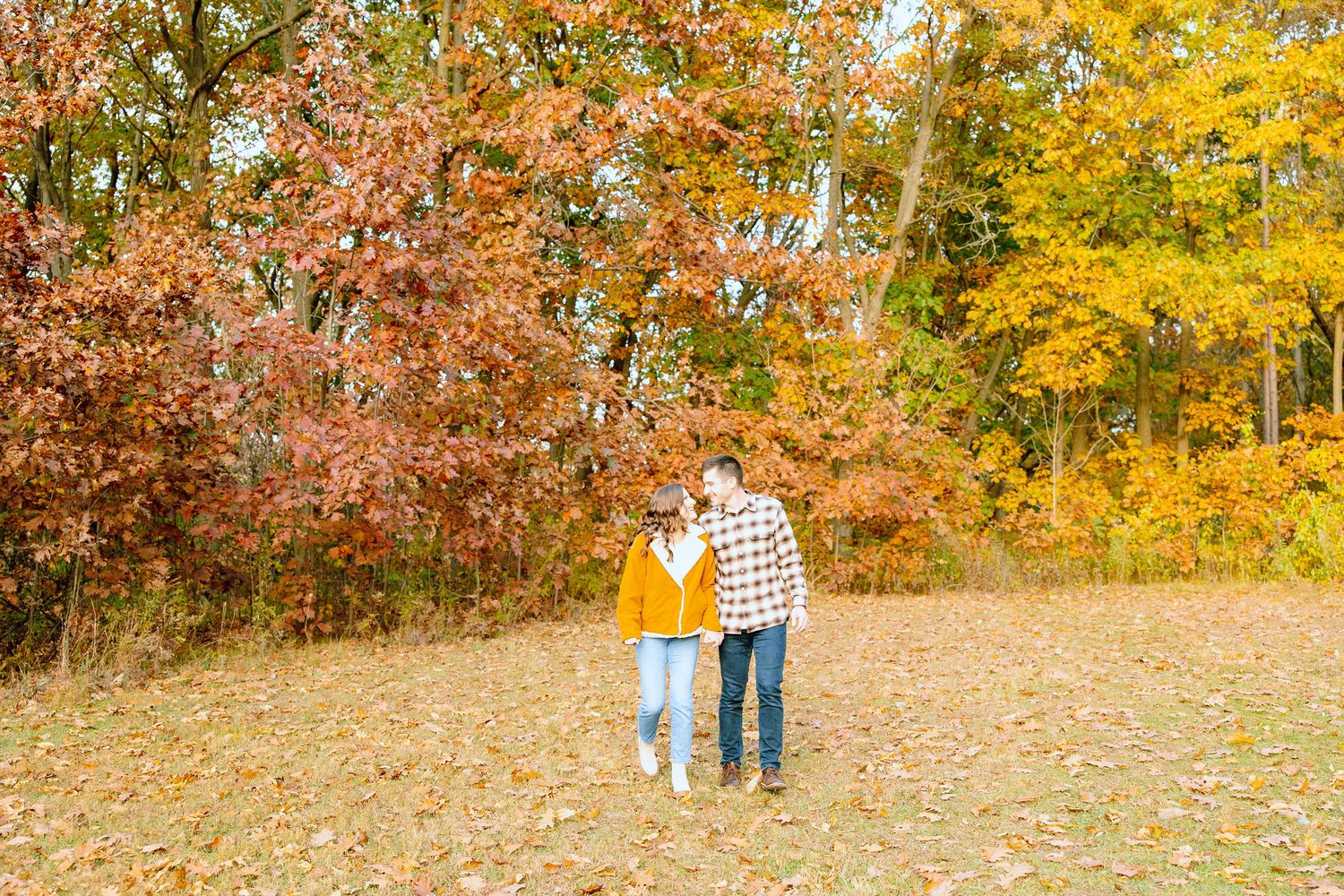 Engaged couple walking in forest at Nichols Arboretum fall engagement session in Ann Arbor, MI