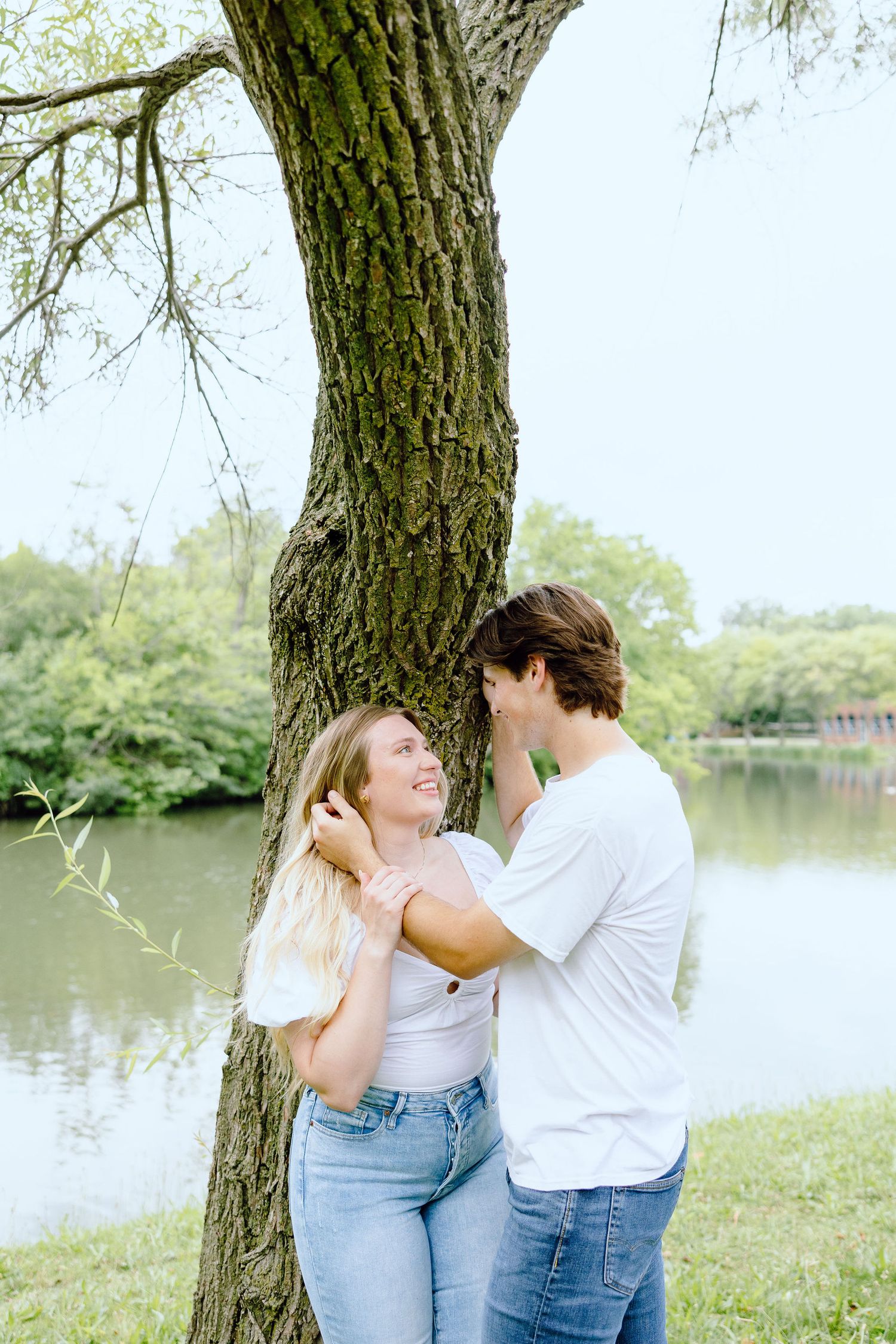 Engaged couple kissing against tree at Greenfield Village in Dearborn, MI