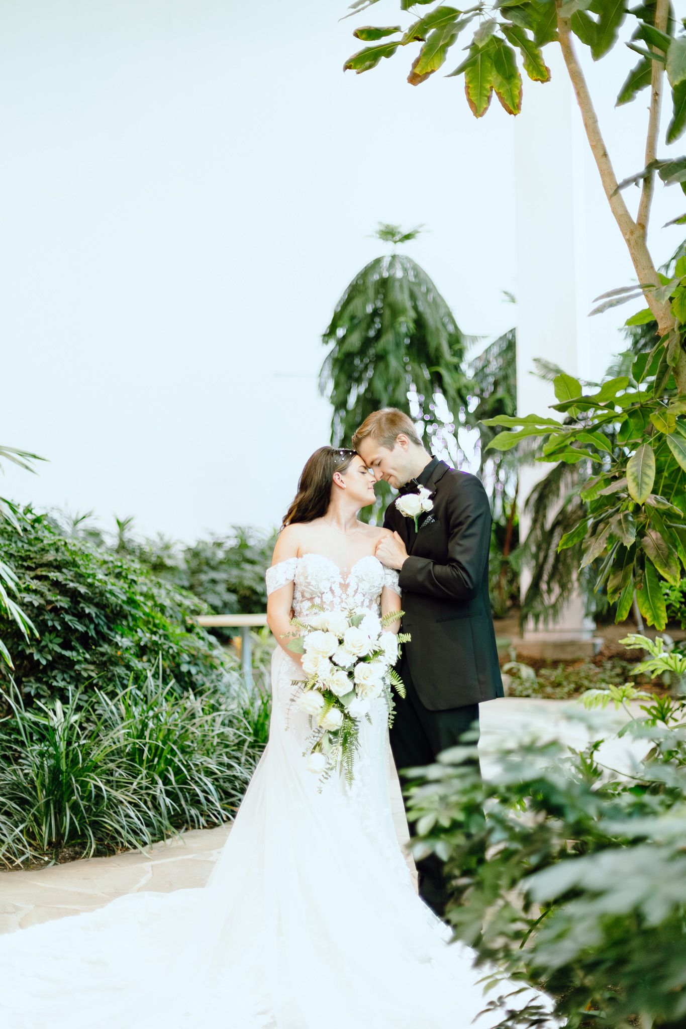 Bride and groom leaning forehead in a timeless greenhouse wedding in Southfield, MI