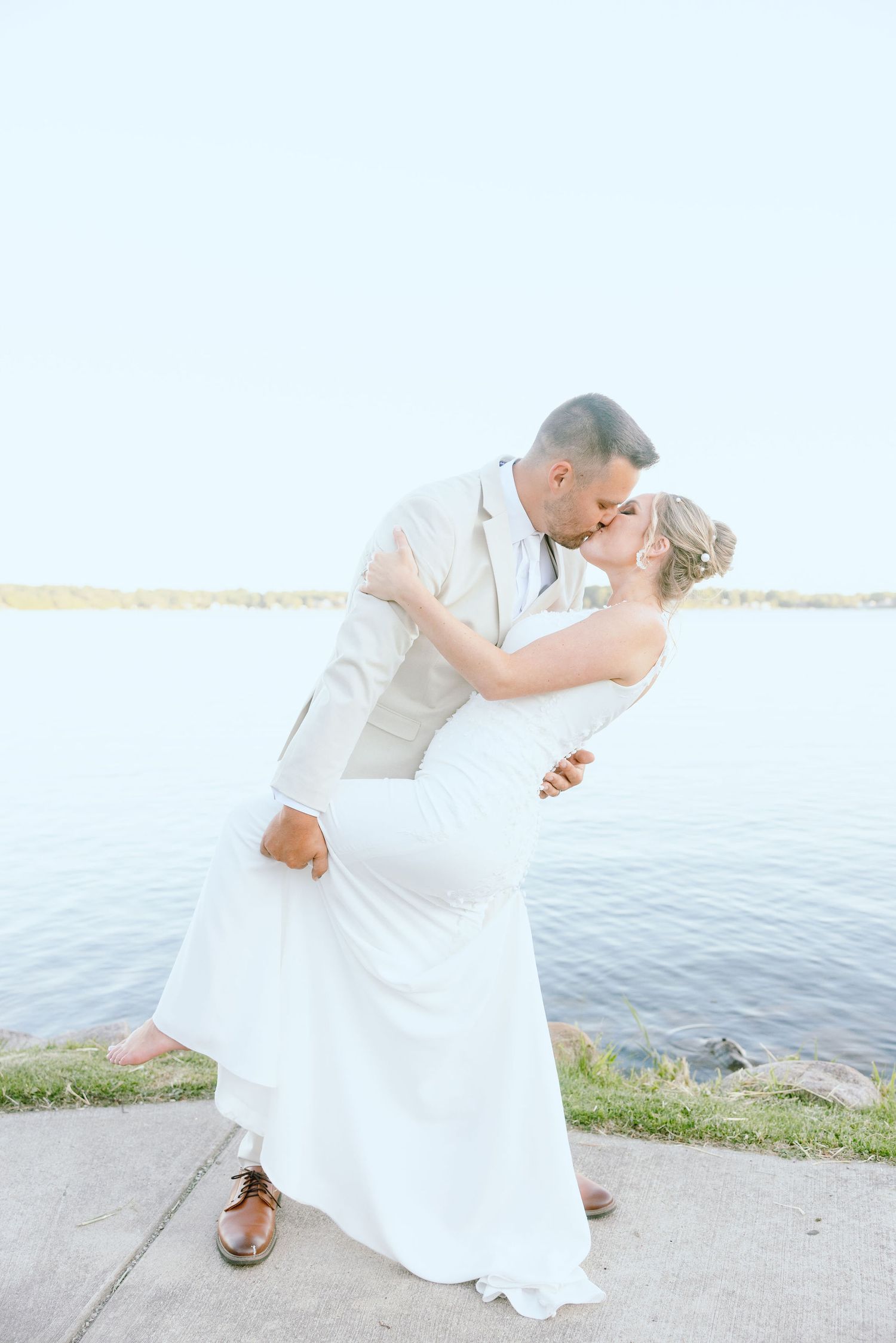 Married couple dipping on lake during golden hour at Lapeer Country Club wedding in Michigan