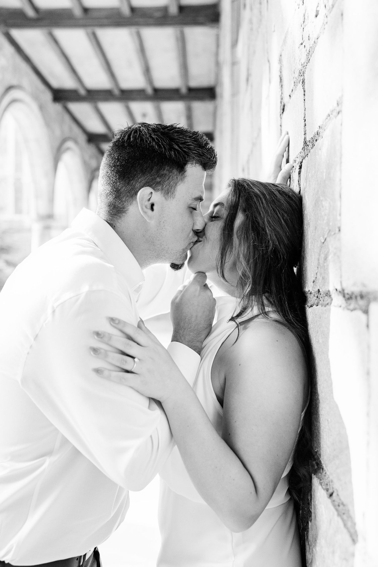 Engaged couple kissing against wall at the University of Michigan Law Quad engagement session in Ann Arbor, MI