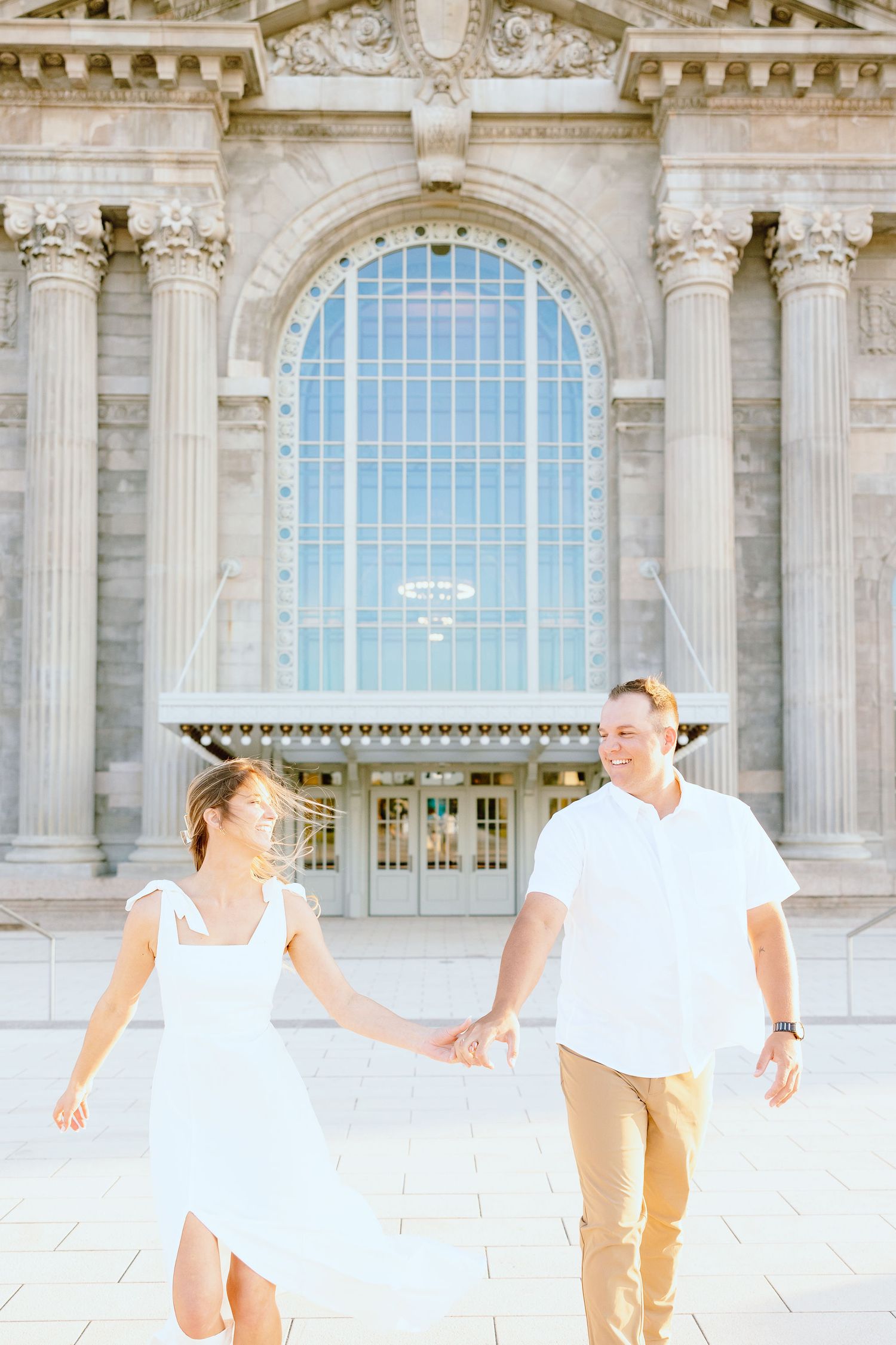 Engaged couple walking and holding hands at Michigan Central Station summer engagement session in Detroit, MI