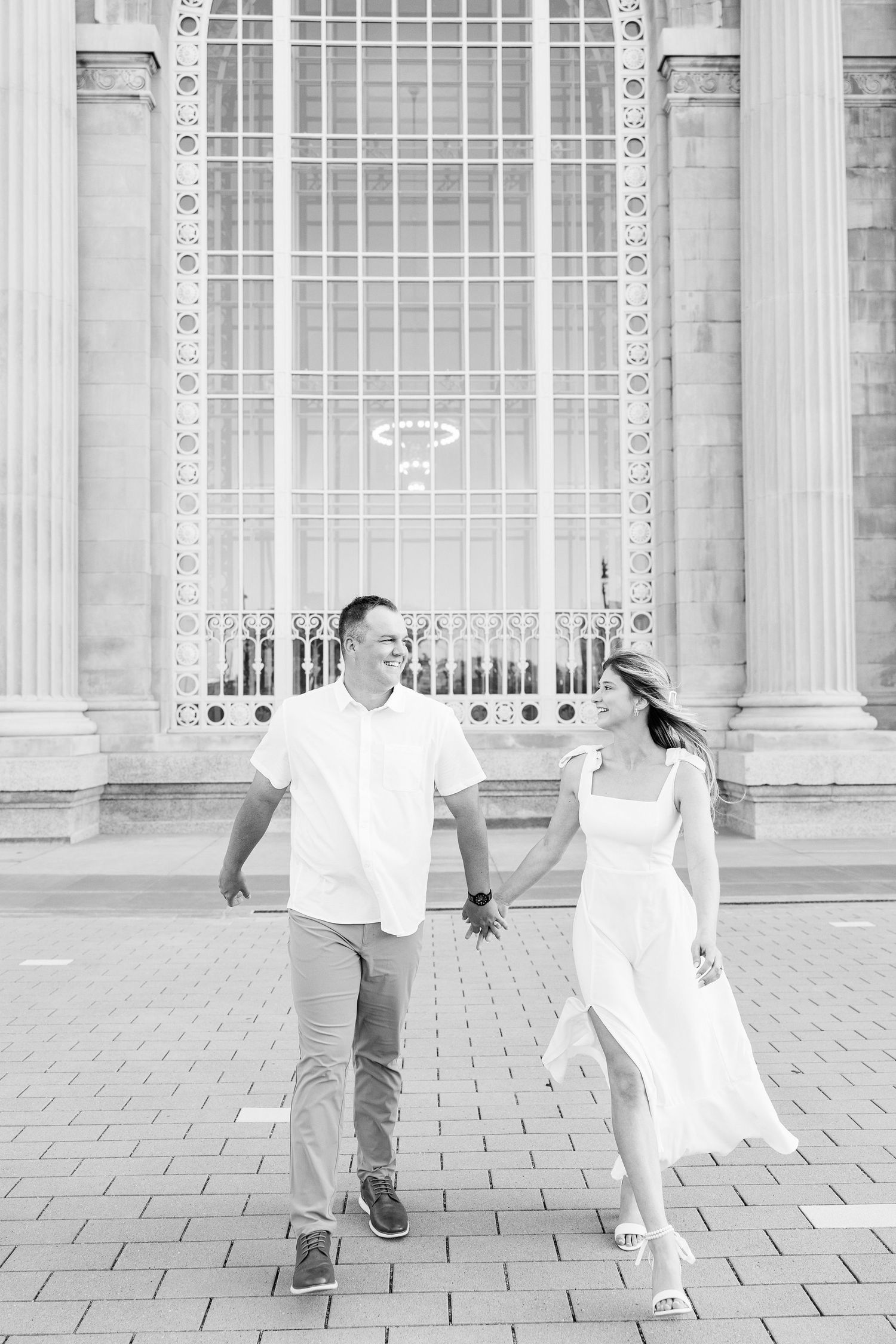 Engaged couple walking and holding hands at Michigan Central Station summer engagement session in Detroit, MI