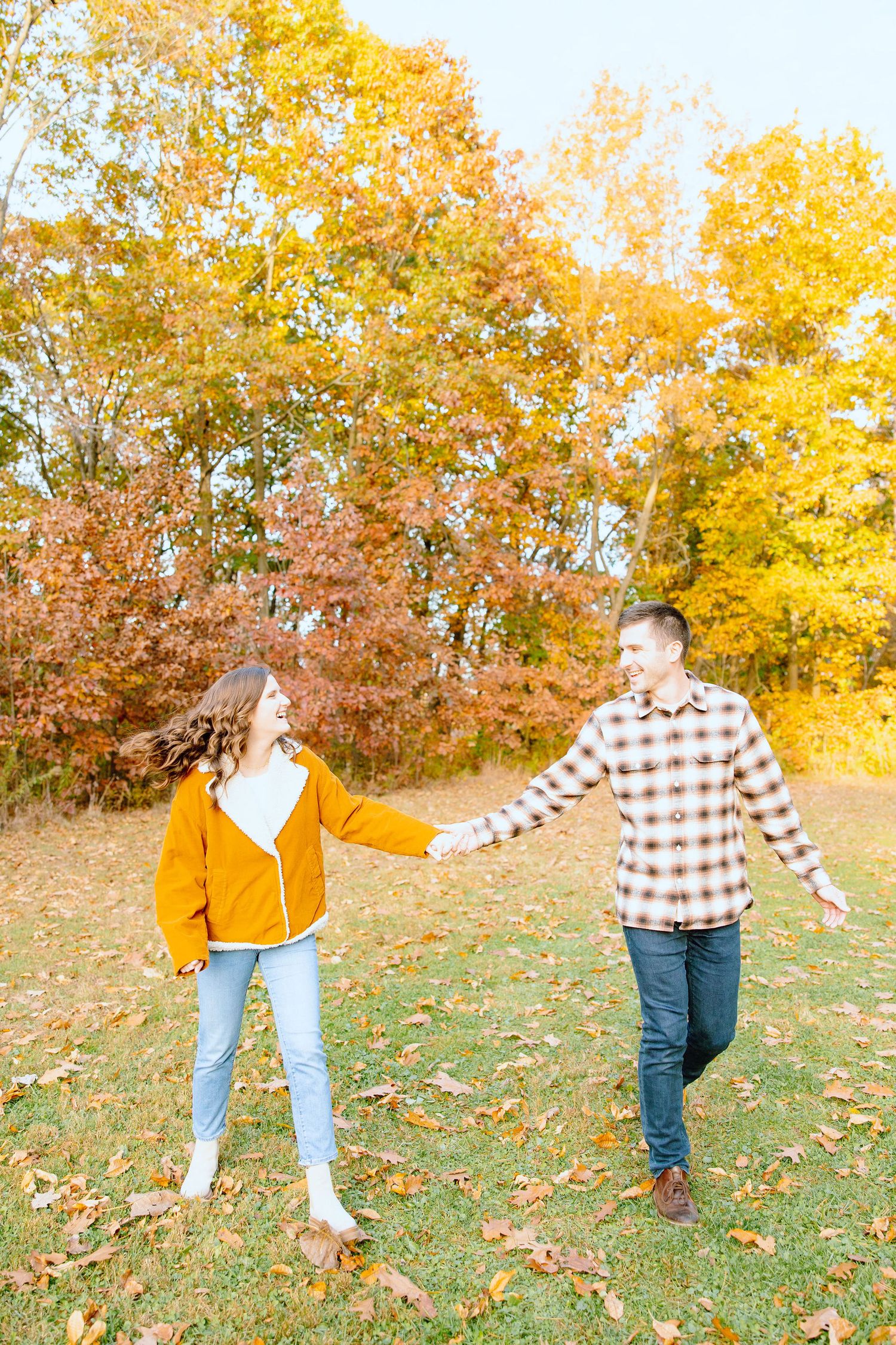 Engaged couple walking in forest at Nichols Arboretum fall engagement session in Ann Arbor, MI