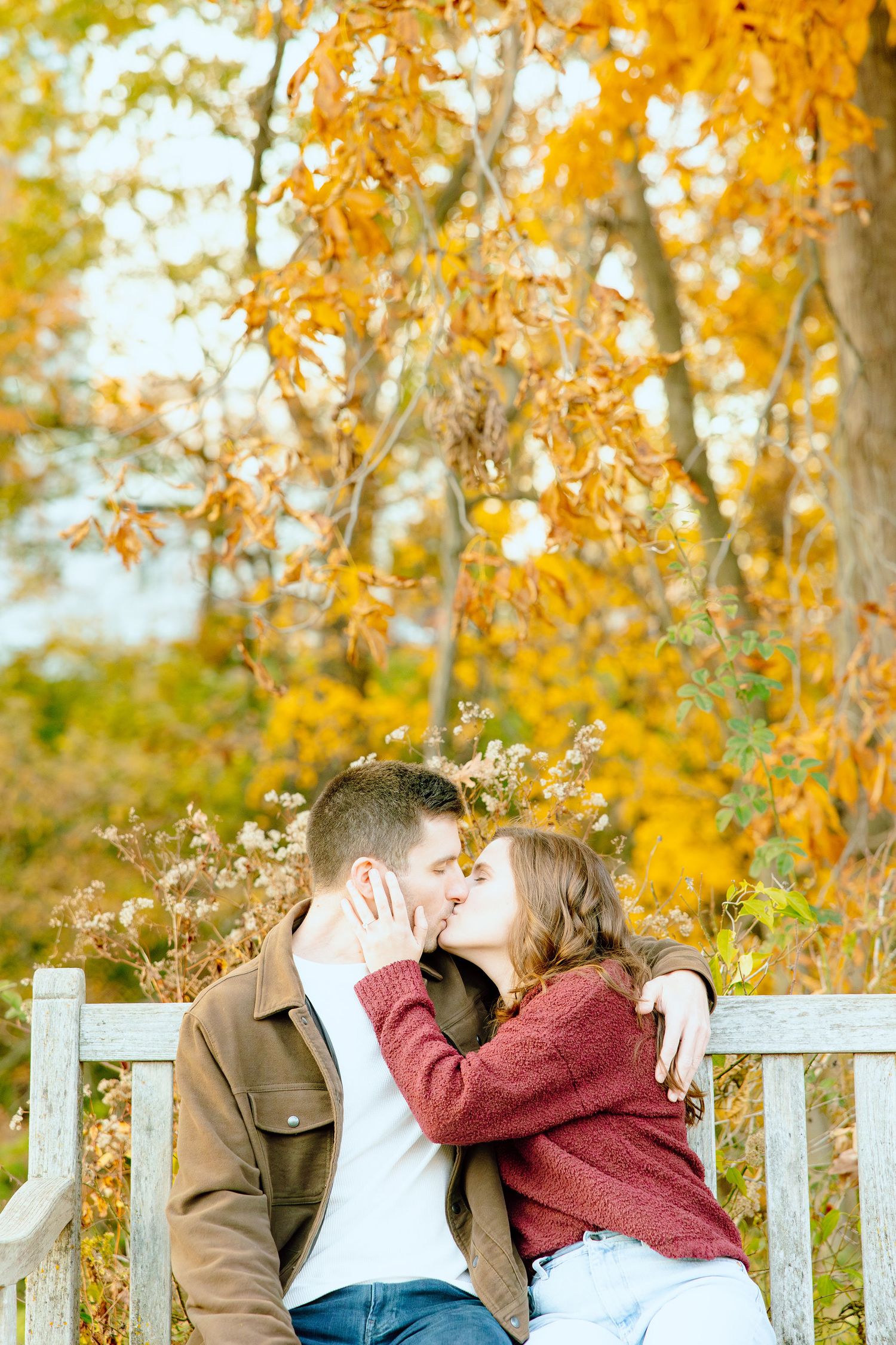 Engaged couple kissing on bench at Nichols Arboretum in Ann Arbor, MI