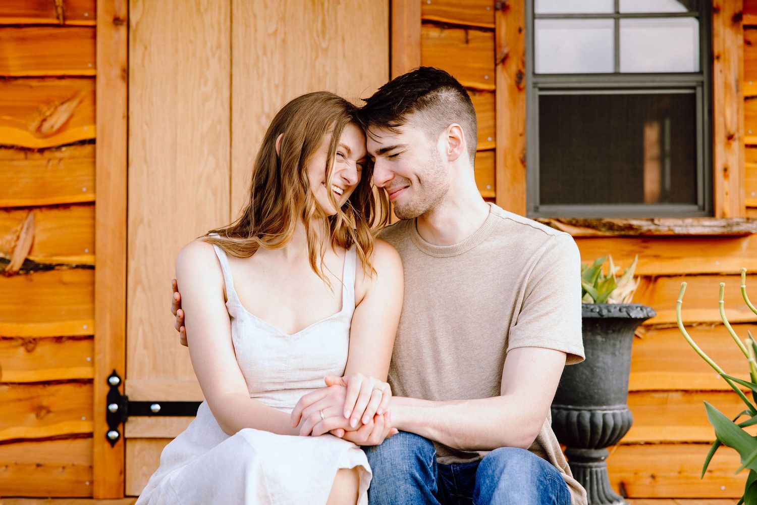 Engaged couple sitting on bench at DeBuck's tulip field spring engagement session in Belleville, MI