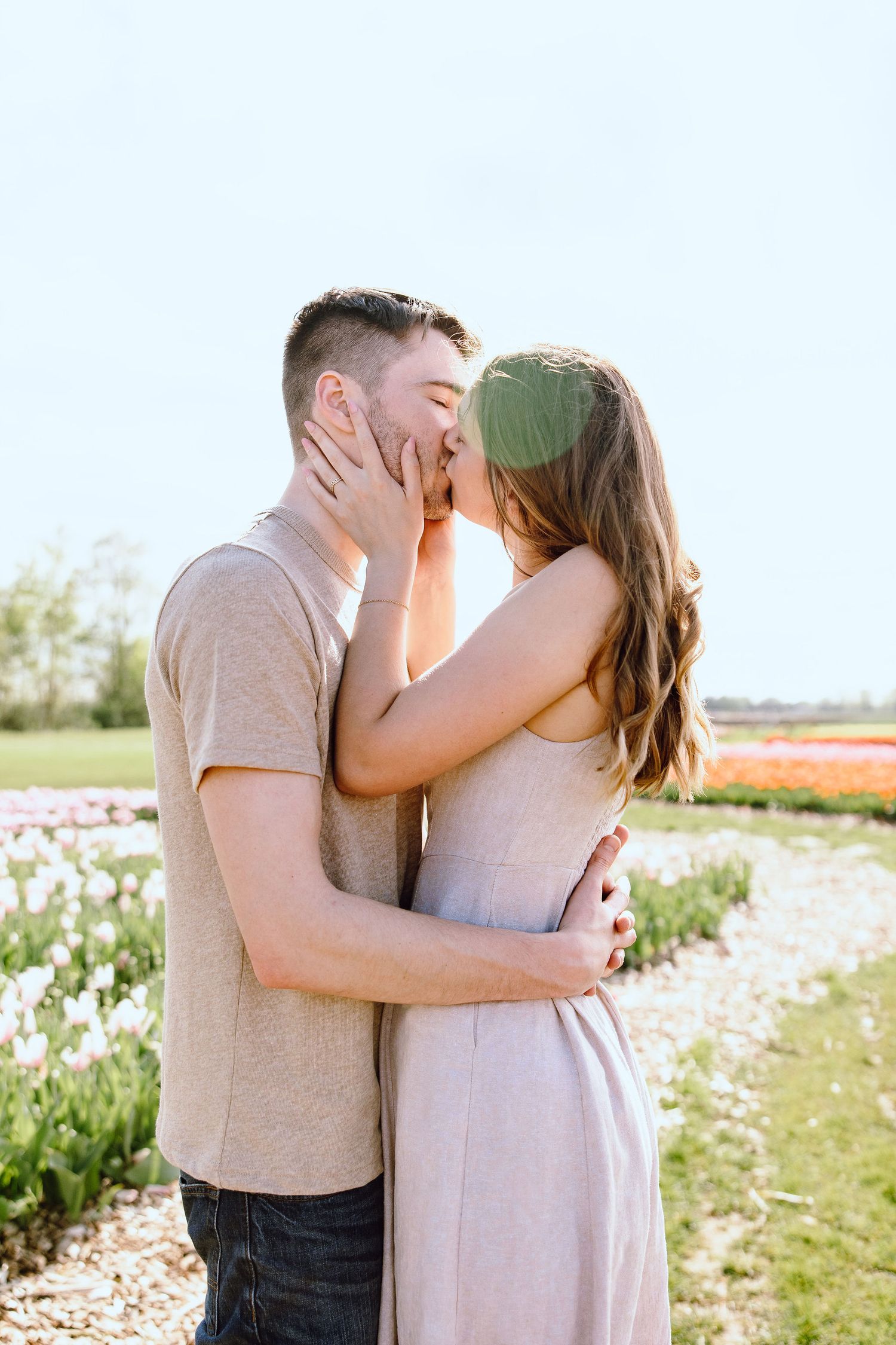 Engaged couple kissing at DeBuck's tulip field spring engagement session in Belleville, MI