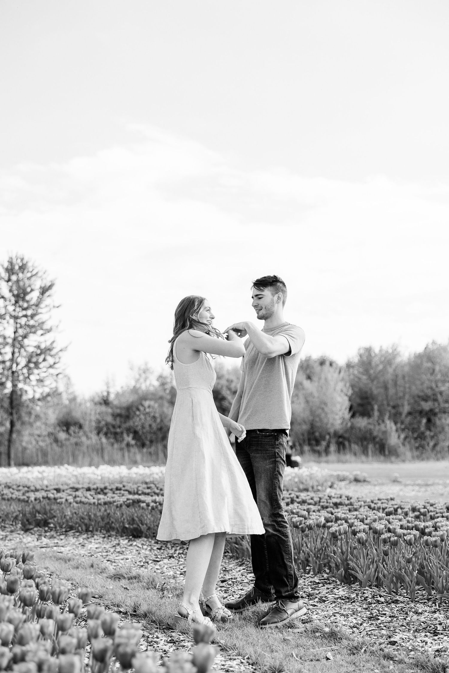 Engaged couple twirling at DeBuck's tulip field spring engagement session in Belleville, MI