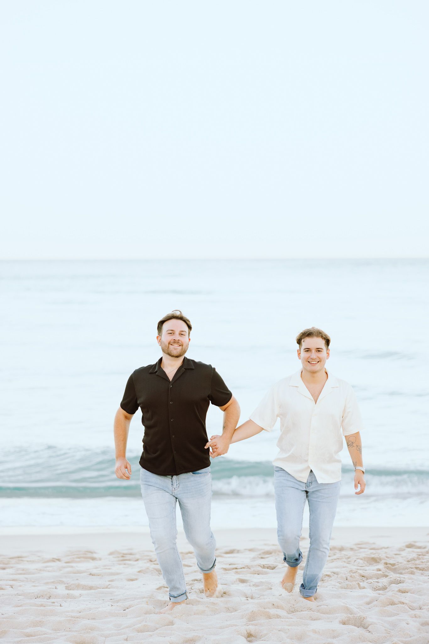 LGBTQ+ couple running and holding hands on North Miami Beach in Florida