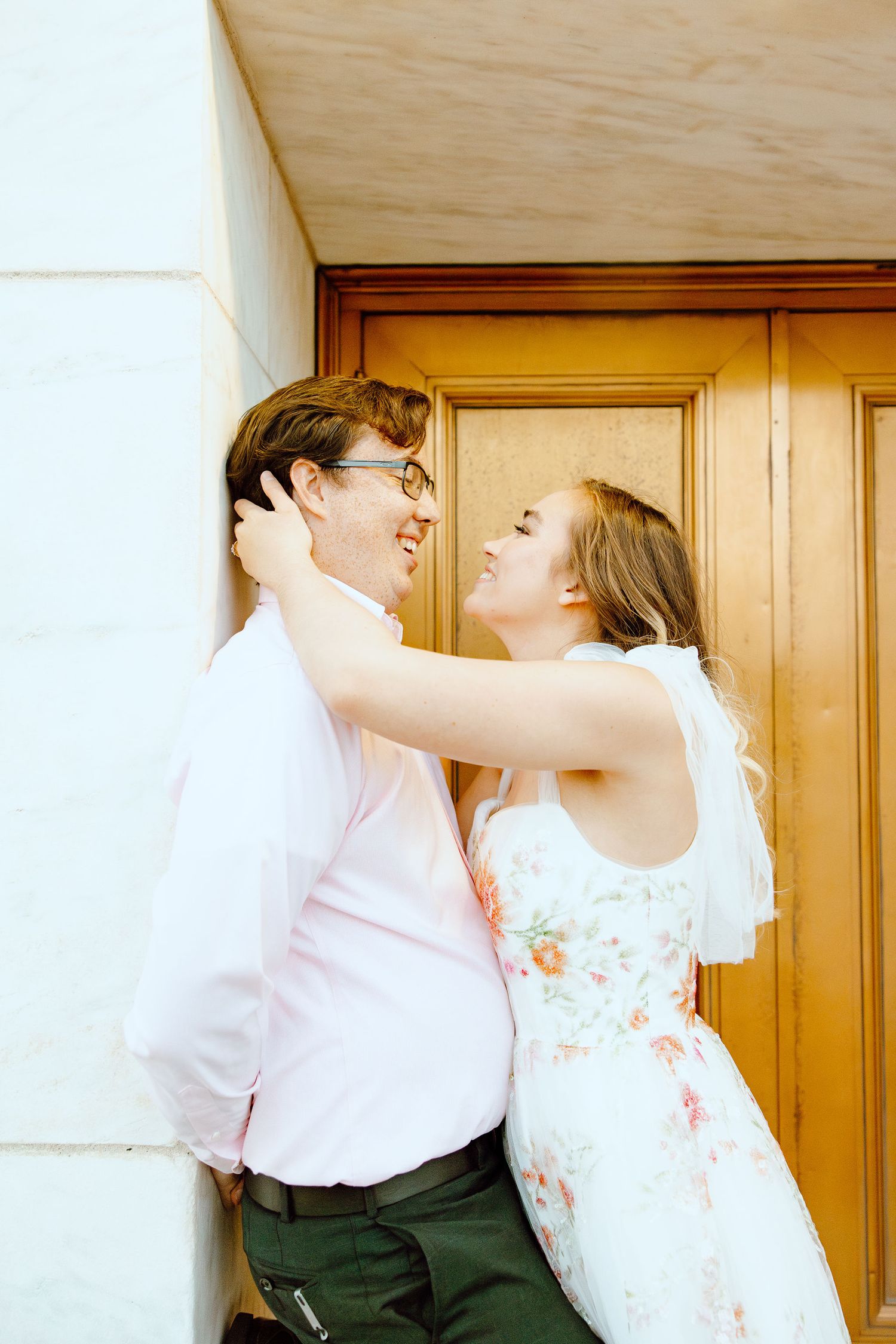 Engaged couple leaning against wall at Belle Isle summer engagement session in Detroit, MI