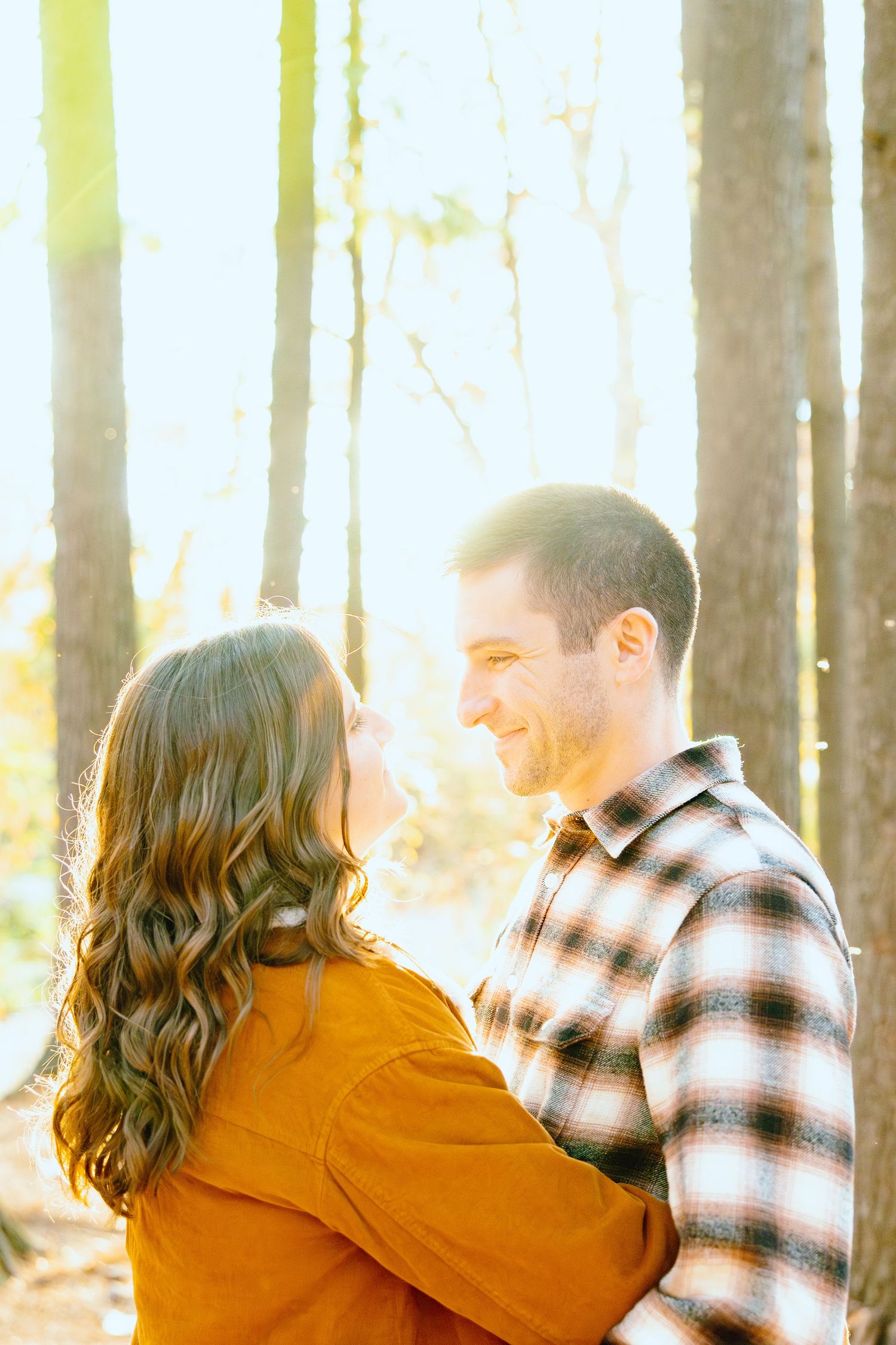 Engaged couple embracing in forest at Nichols Arboretum fall engagement session in Ann Arbor, MI