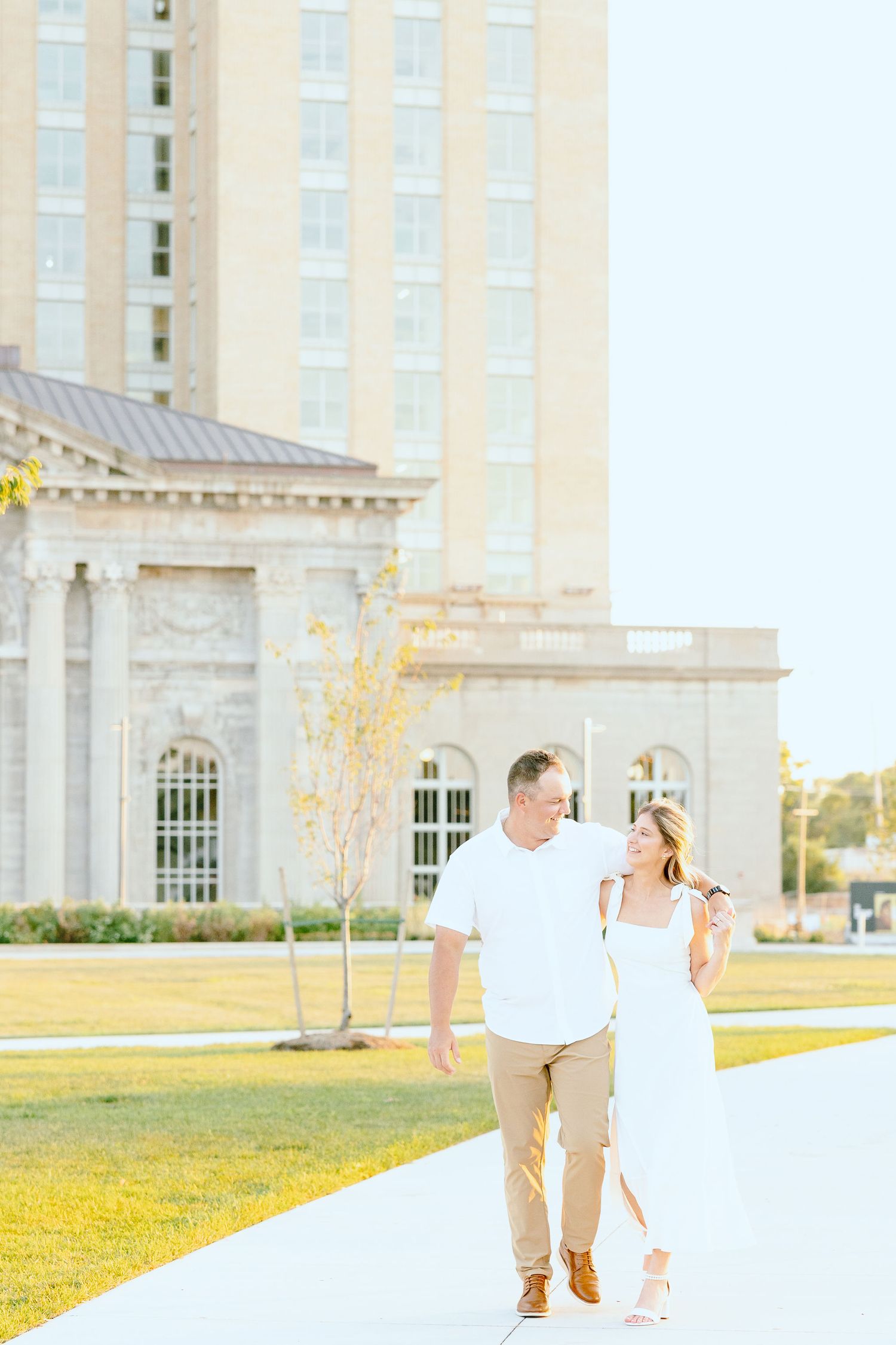 Engaged couple walking and holding hands at Michigan Central Station summer engagement session in Detroit, MI