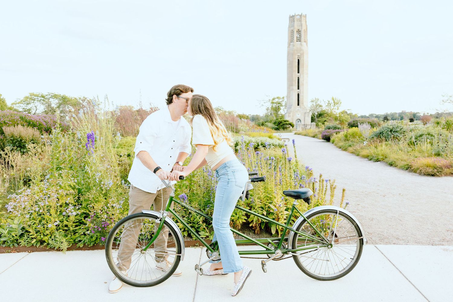 Engaged couple kissing on tandem bike at Belle Isle summer engagement session in Detroit, MI