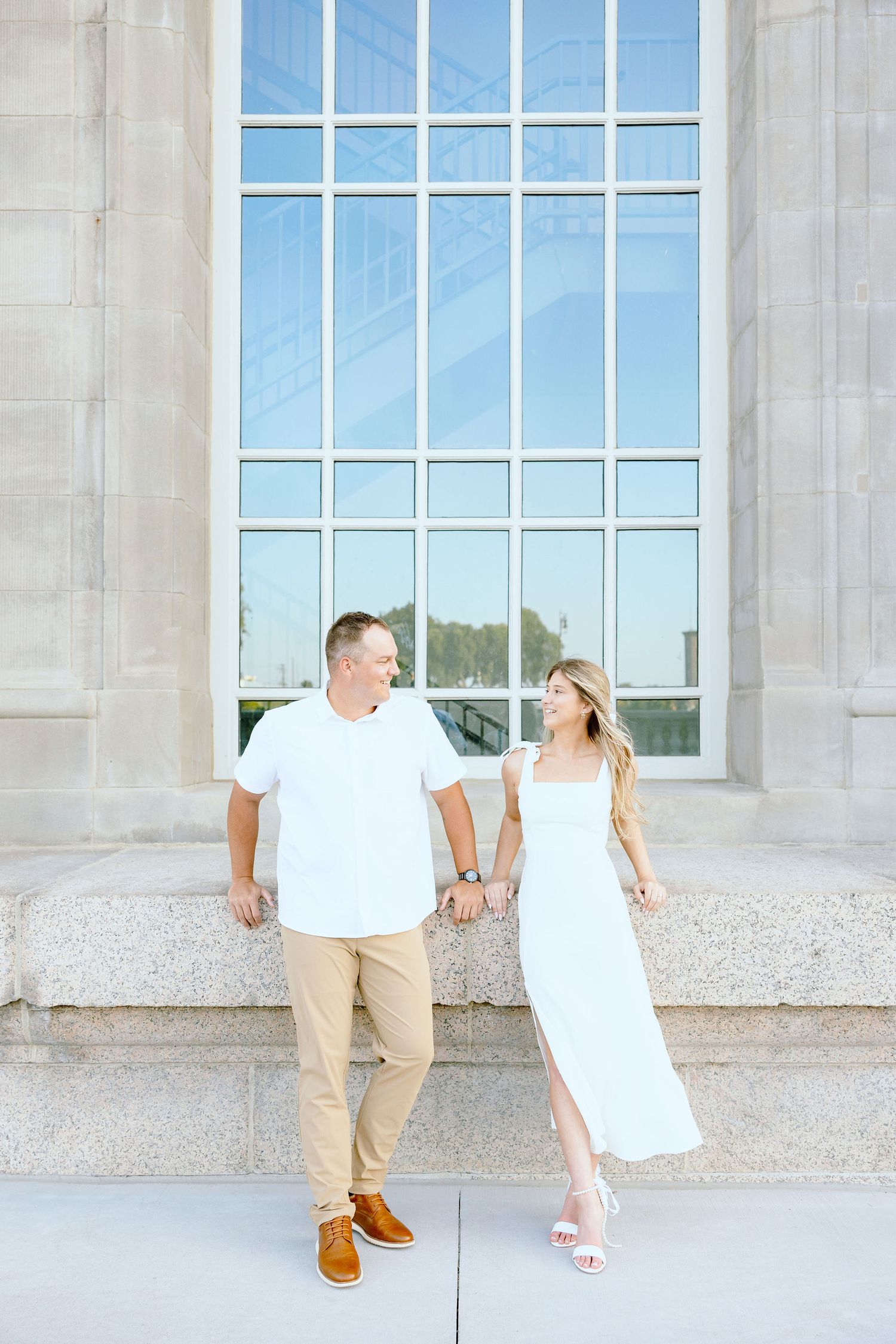 Engaged couple sitting at Michigan Central Station summer engagement session in Detroit, MI
