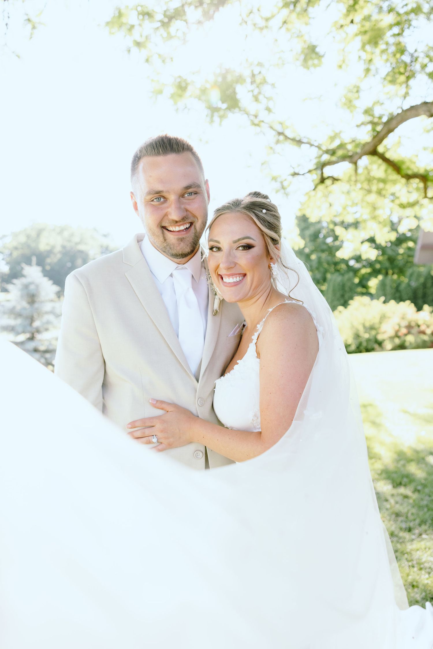 Married couple embracing under veil at Lapeer Country Club wedding in Michigan