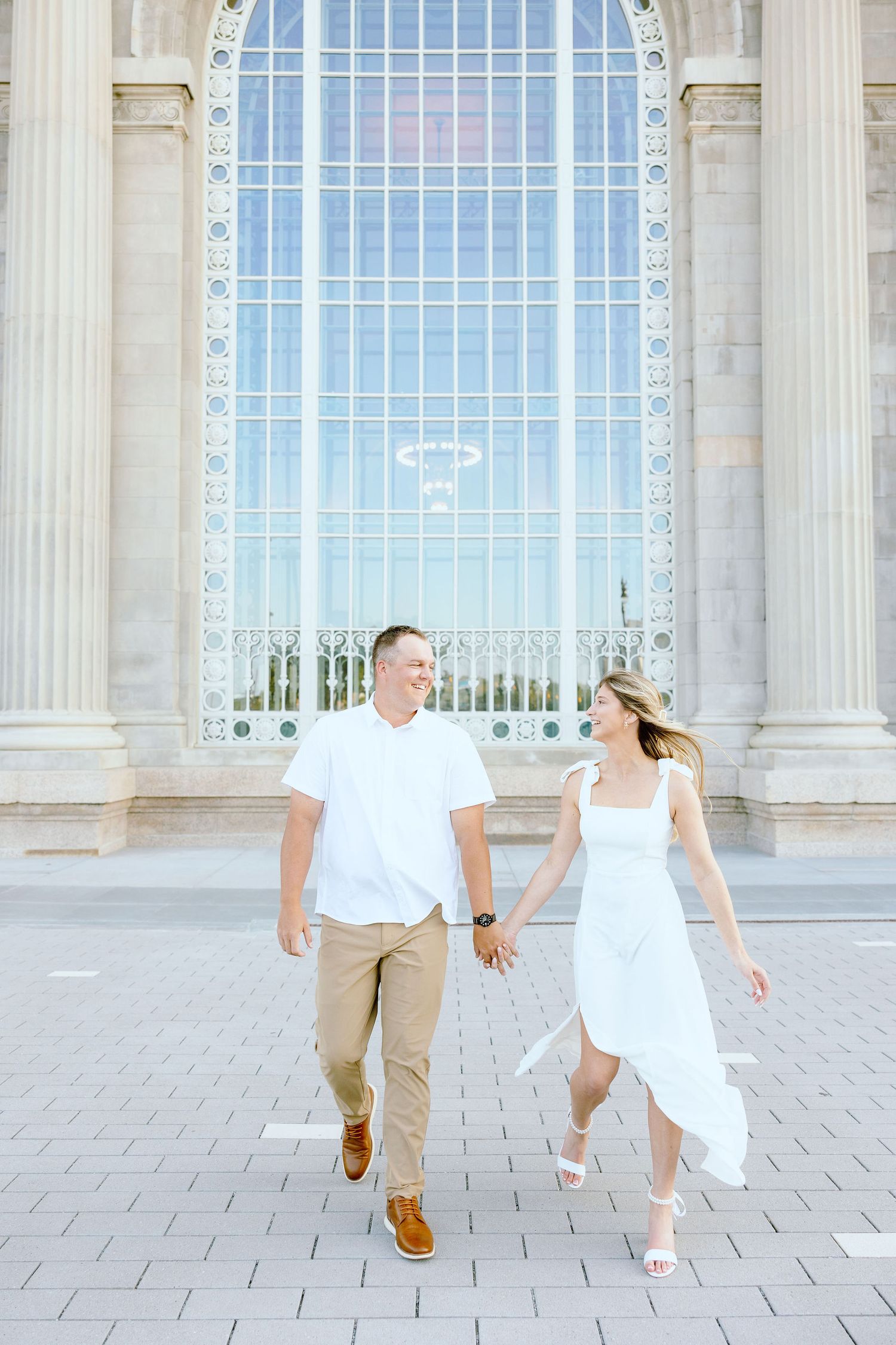 Engaged couple walking and holding hands at Michigan Central Station summer engagement session in Detroit, MI