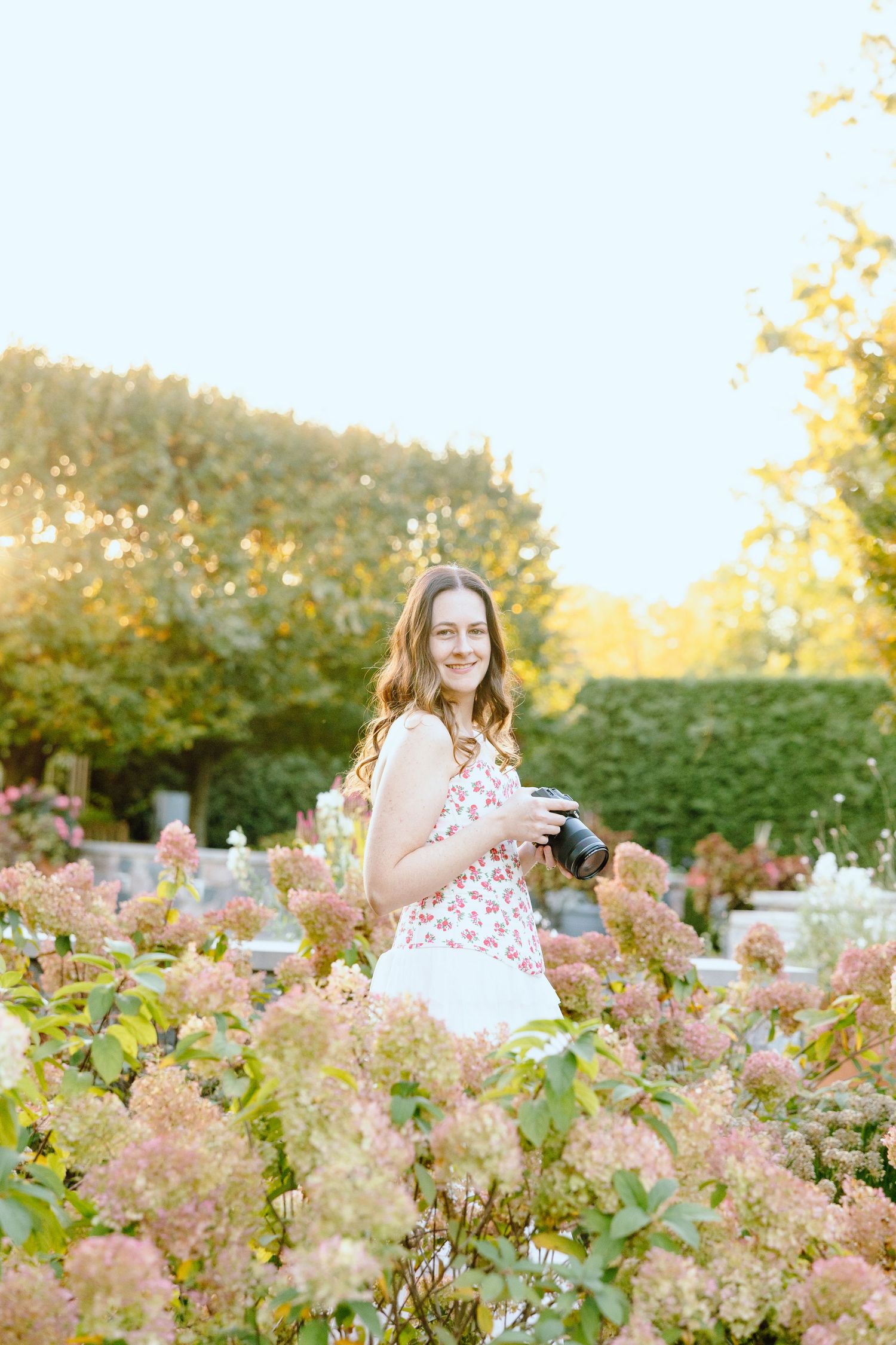 Owner of Perri Foster Photography standing in garden with camera