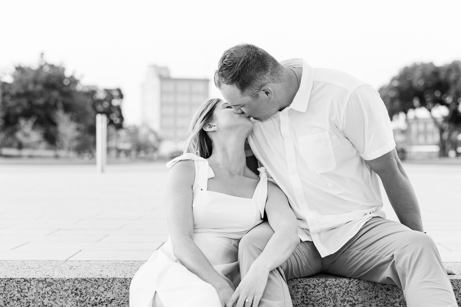 Engaged couple kissing on bench at Michigan Central Station in Detroit, MI