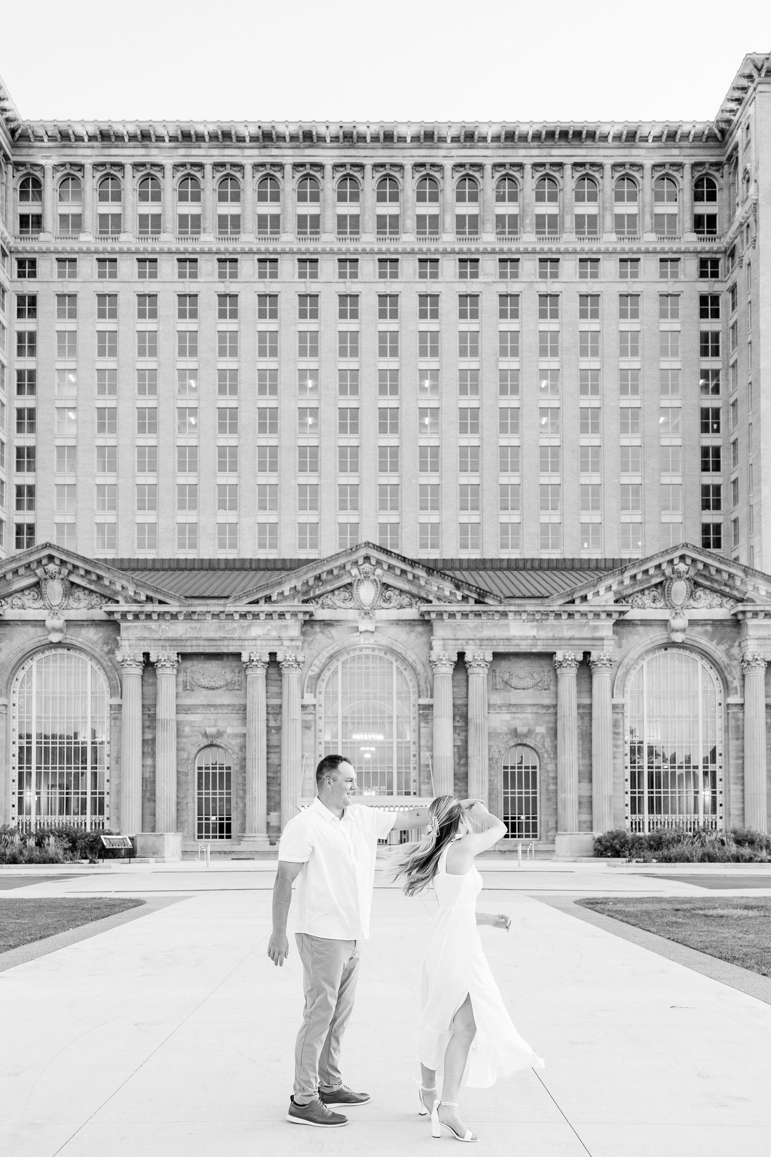 Engaged couple twirling at Michigan Central Station summer engagement session in Detroit, MI