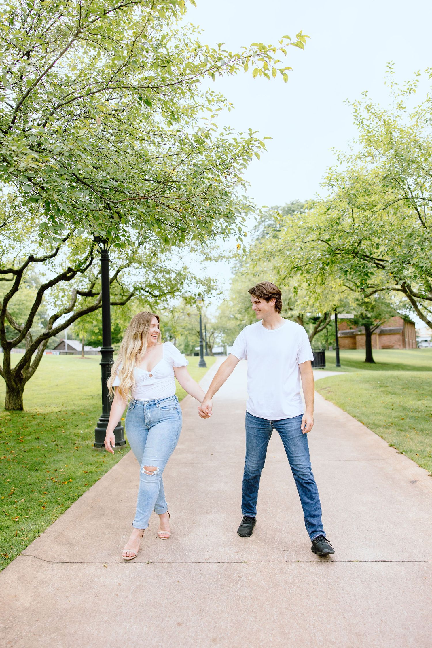 Engaged couple walking and holding hands at Greenfield Village in Dearborn, MI