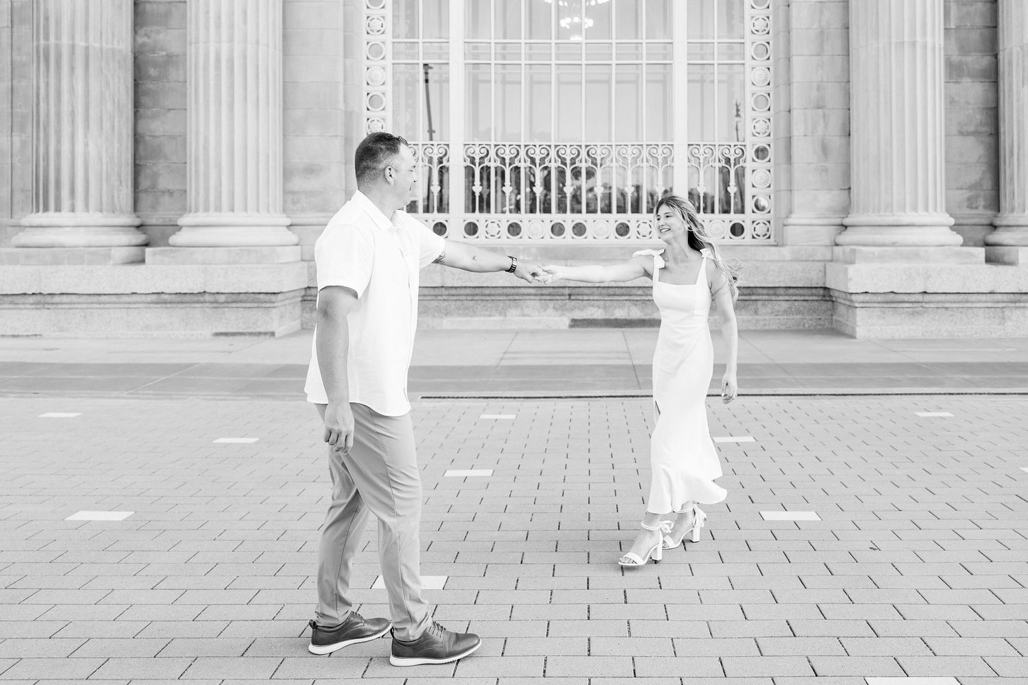 Engaged couple twirling at Michigan Central Station summer engagement session in Detroit, MI