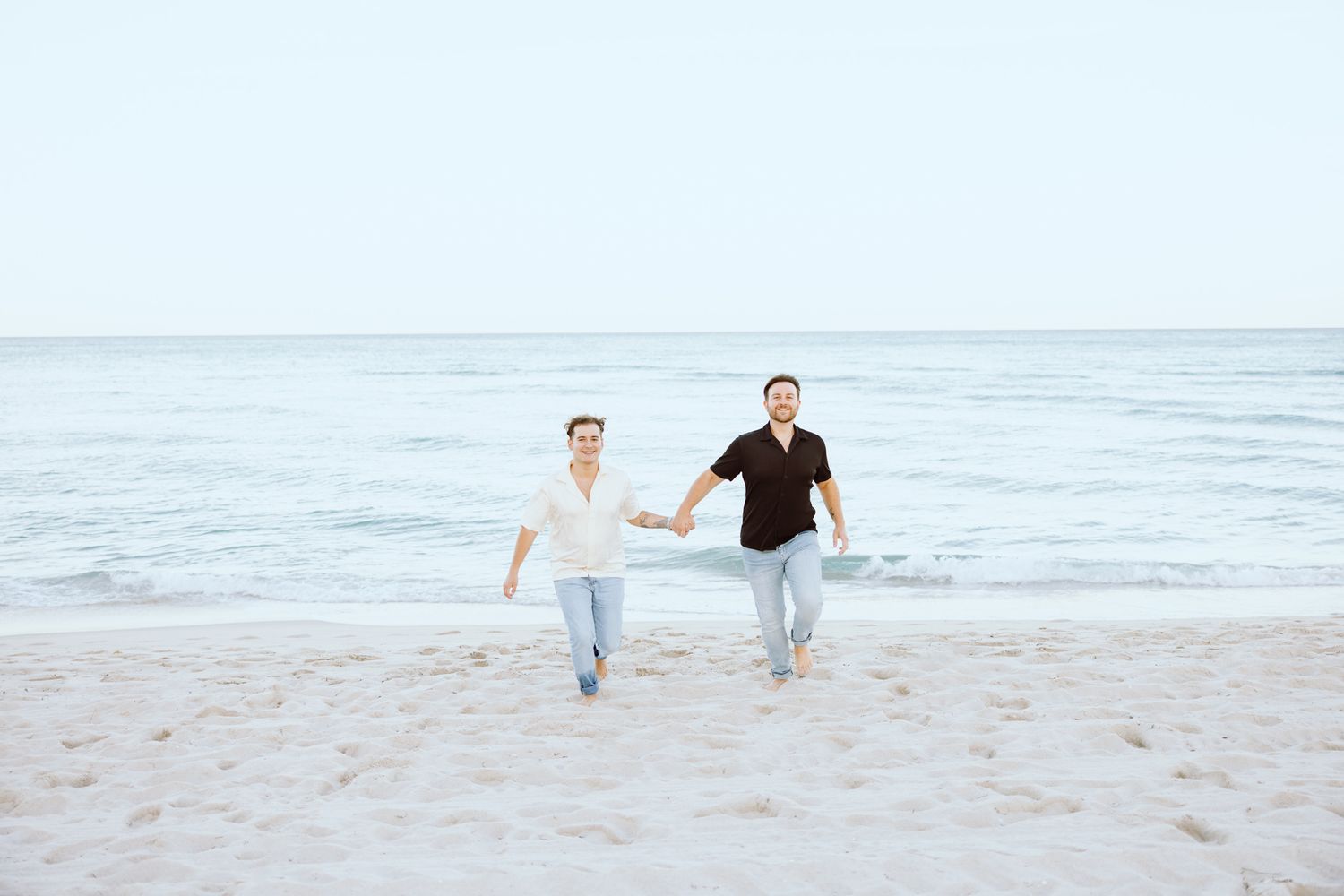 LGBTQ+ couple running and holding hands on North Miami Beach in Florida