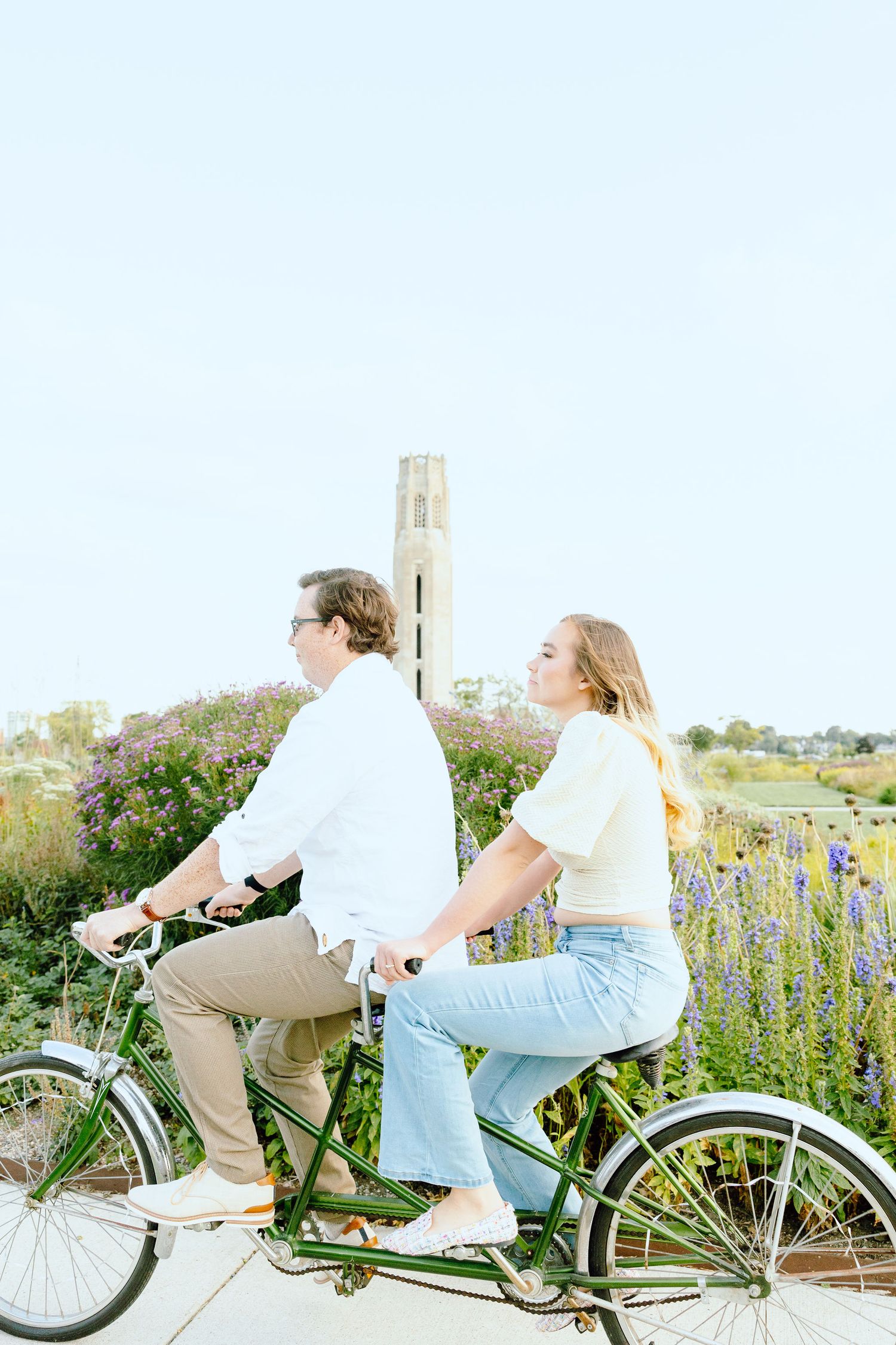 Engaged couple biking on tandem bike at Belle Isle summer engagement session in Detroit, MI