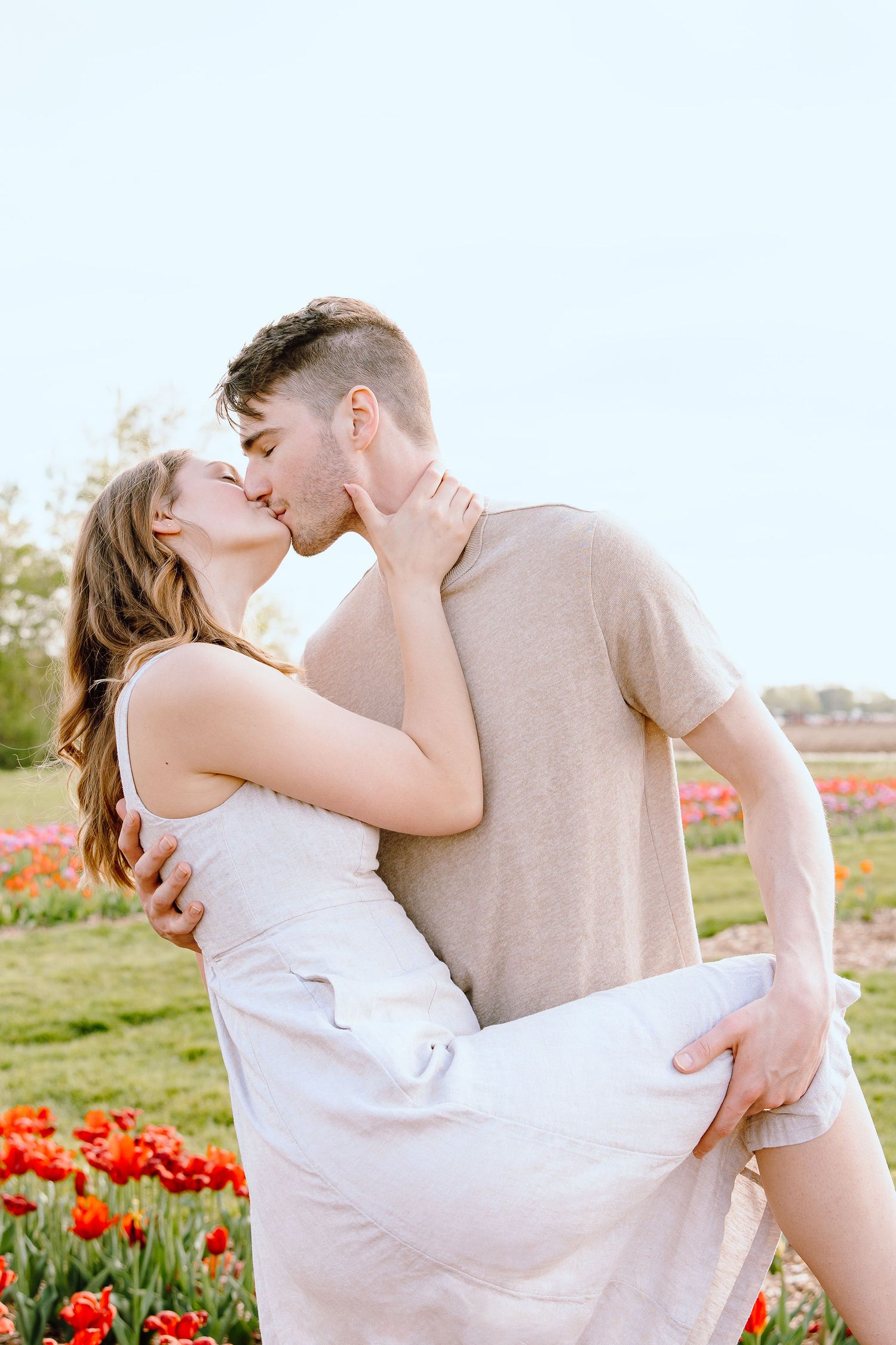 Engaged couple kissing at DeBuck's tulip field spring engagement session in Belleville, MI