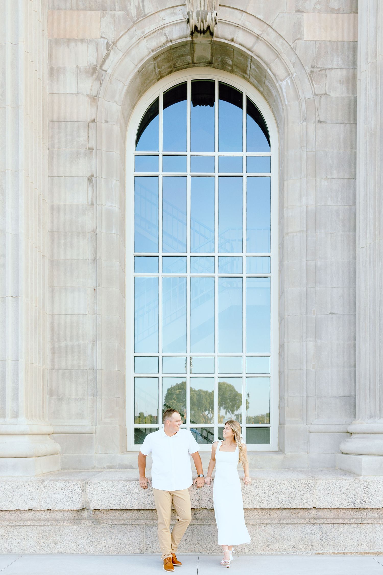 Engaged couple sitting at Michigan Central Station summer engagement session in Detroit, MI