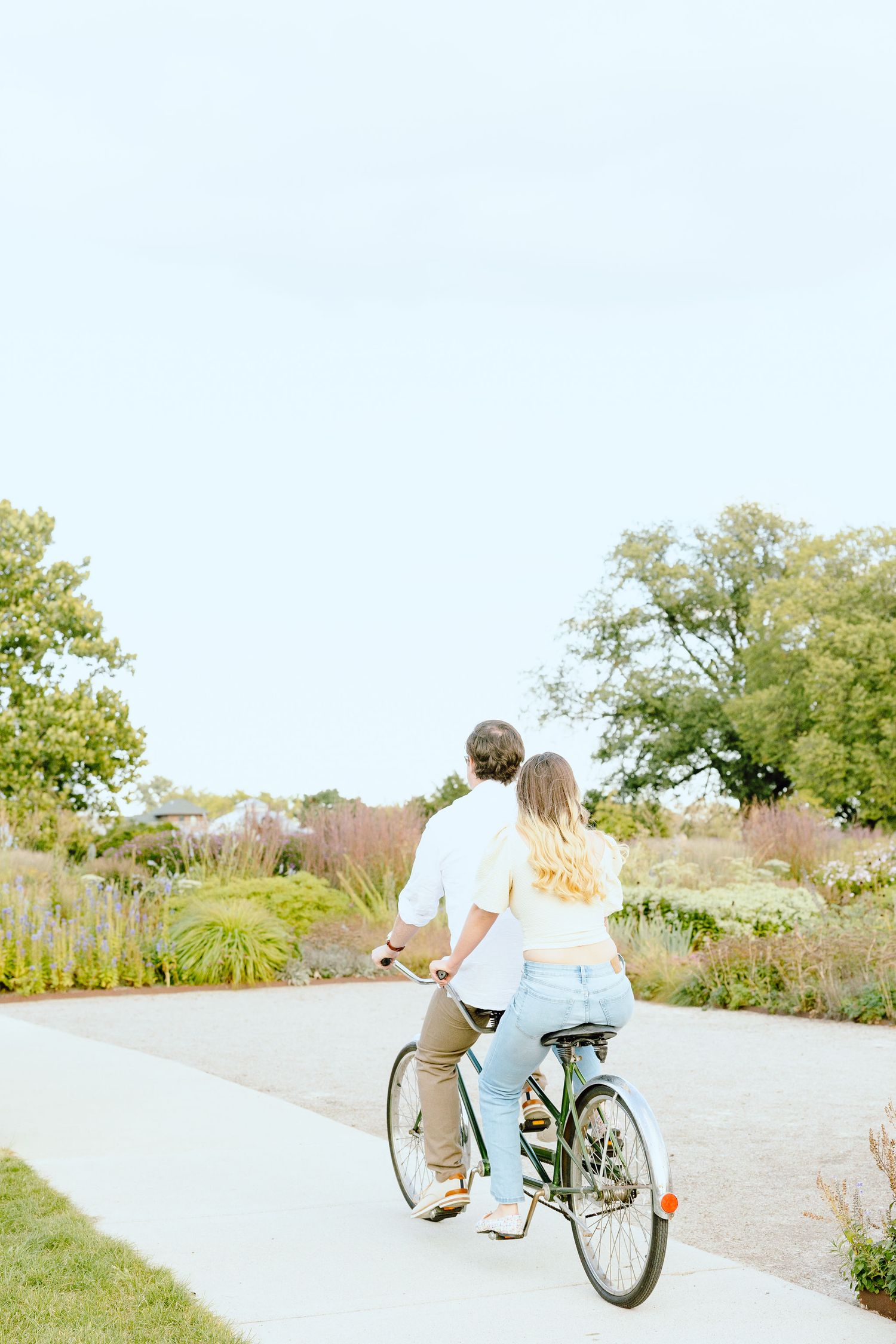 Engaged couple biking on tandem bike at Belle Isle summer engagement session in Detroit, MI