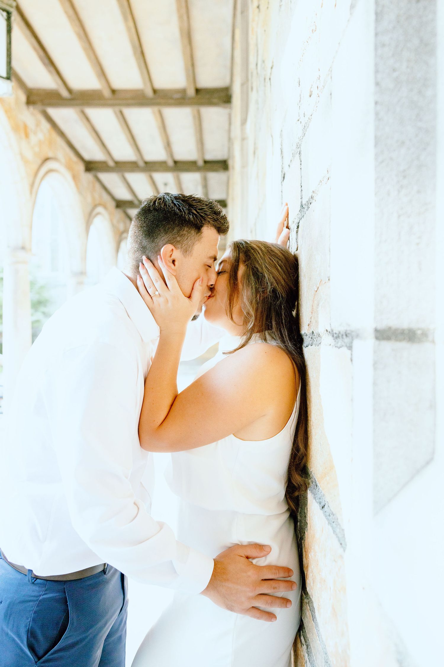 Engaged couple kissing against wall at the University of Michigan Law Quad engagement session in Ann Arbor, MI