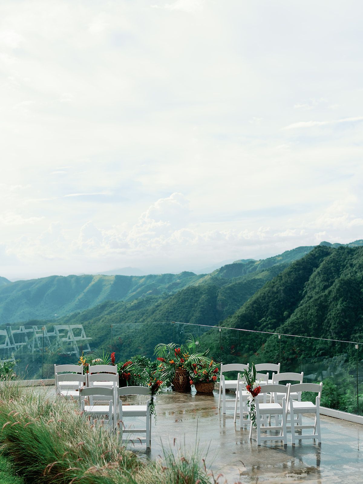 White chairs set up for a mountaintop wedding ceremony with dramatic valley views.