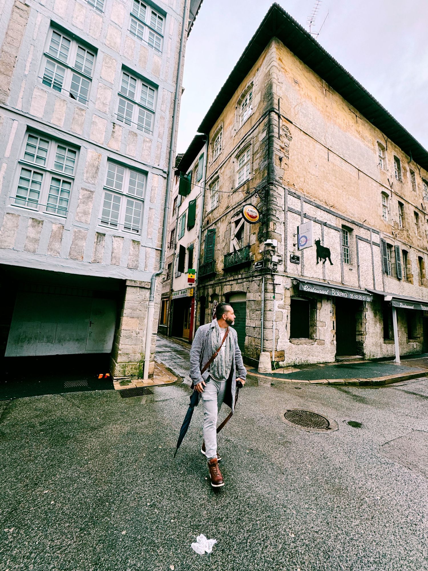 Person in grey coat walking through historic stone buildings on a narrow European street.