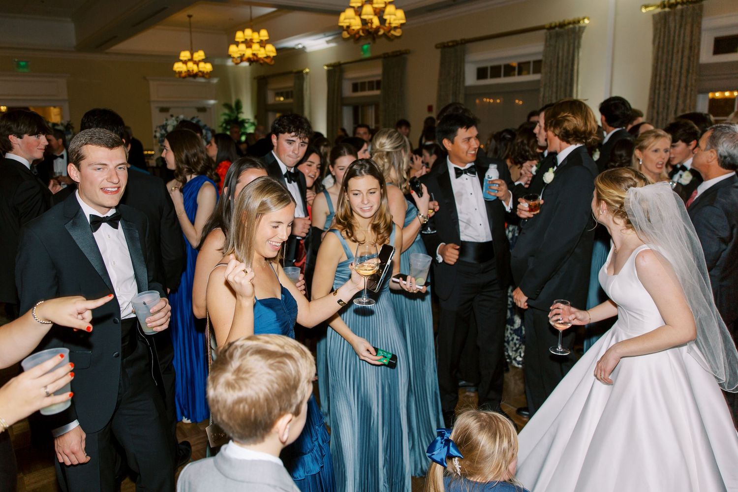 Wedding reception scene with guests mingling and celebrating in formal attire.