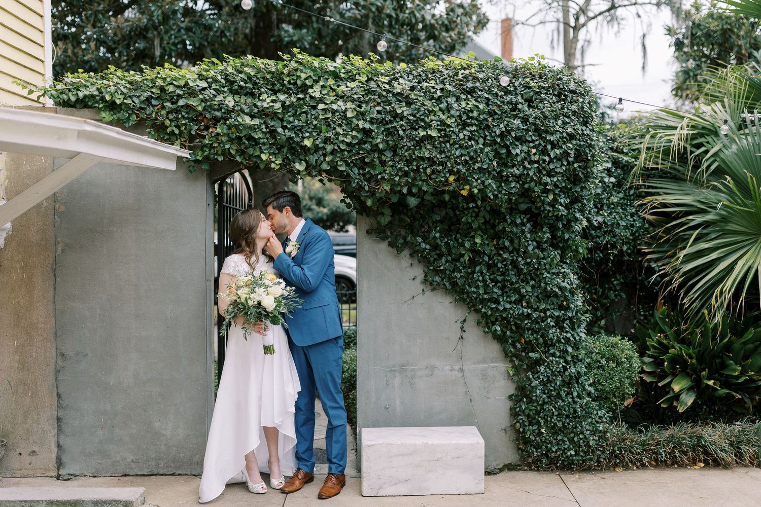 A tender moment against an ivy-covered wall and landscaped garden setting.