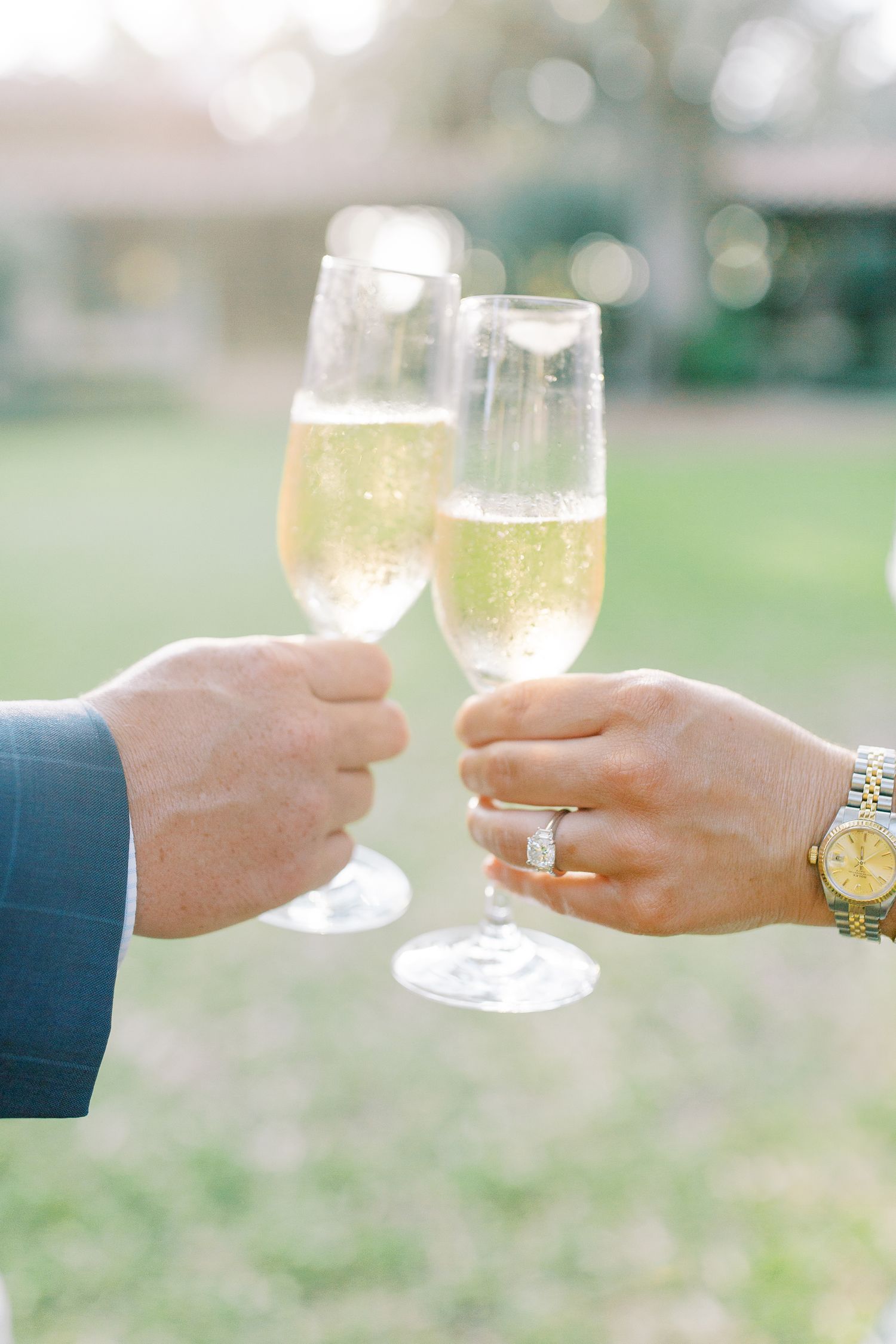 Hands toasting with champagne glasses showing engagement ring outdoors at Sea Island in St. Simons.