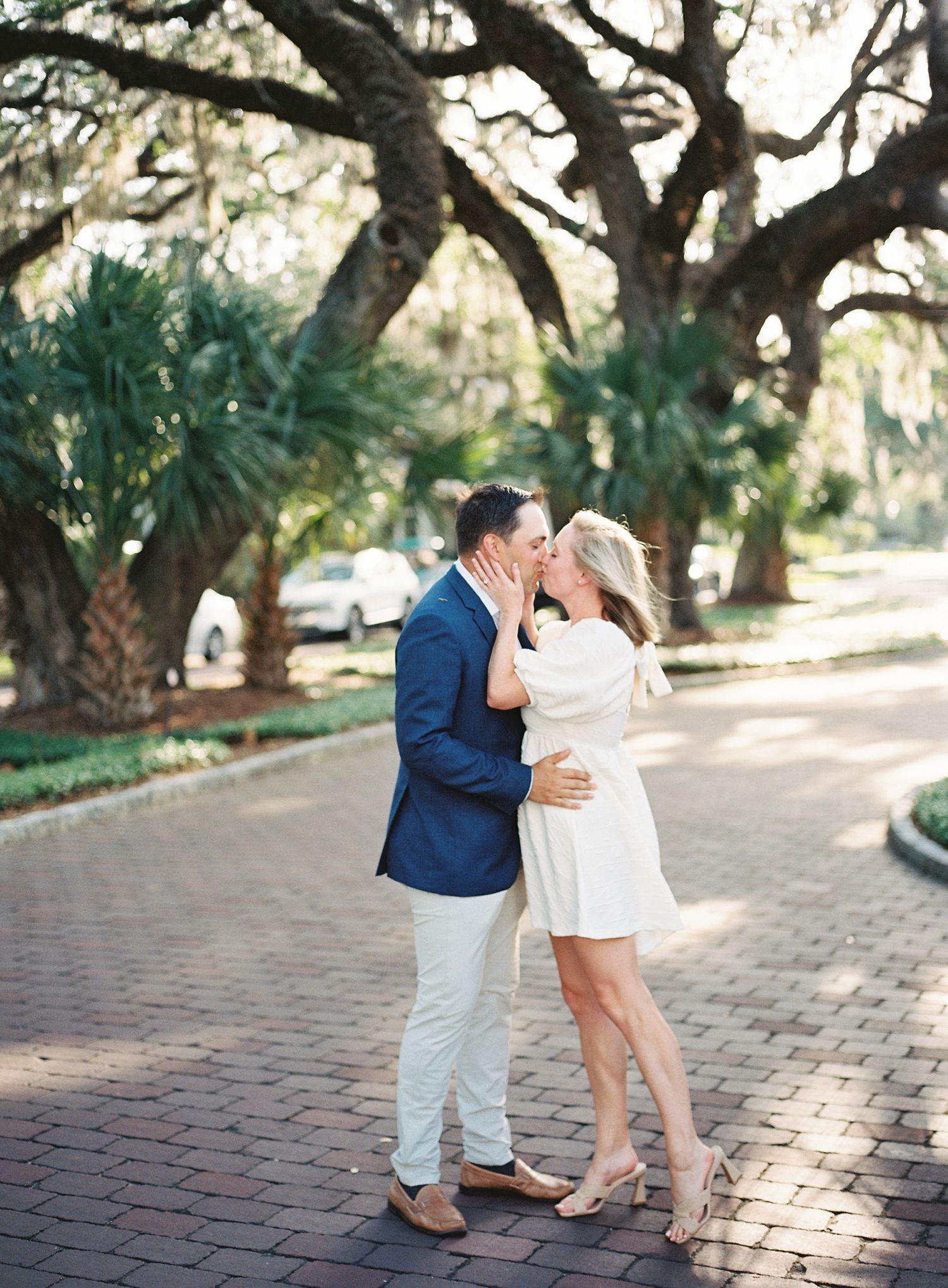 A couple shares an intimate moment on a brick pathway beneath Spanish moss-draped oak trees in Palmetto Bluff.