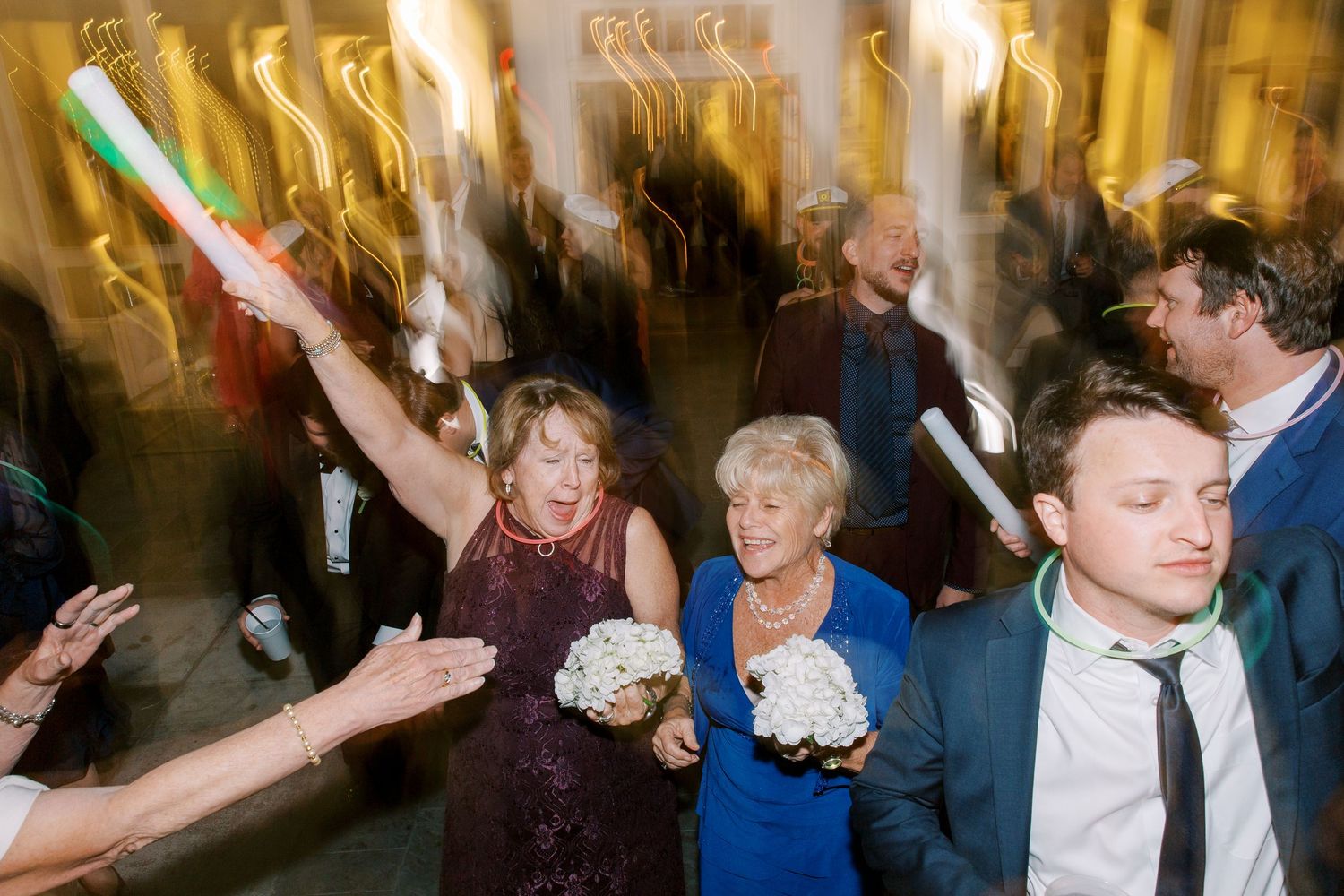People dancing and celebrating at a lively party with motion blur and glowing lights in the background.