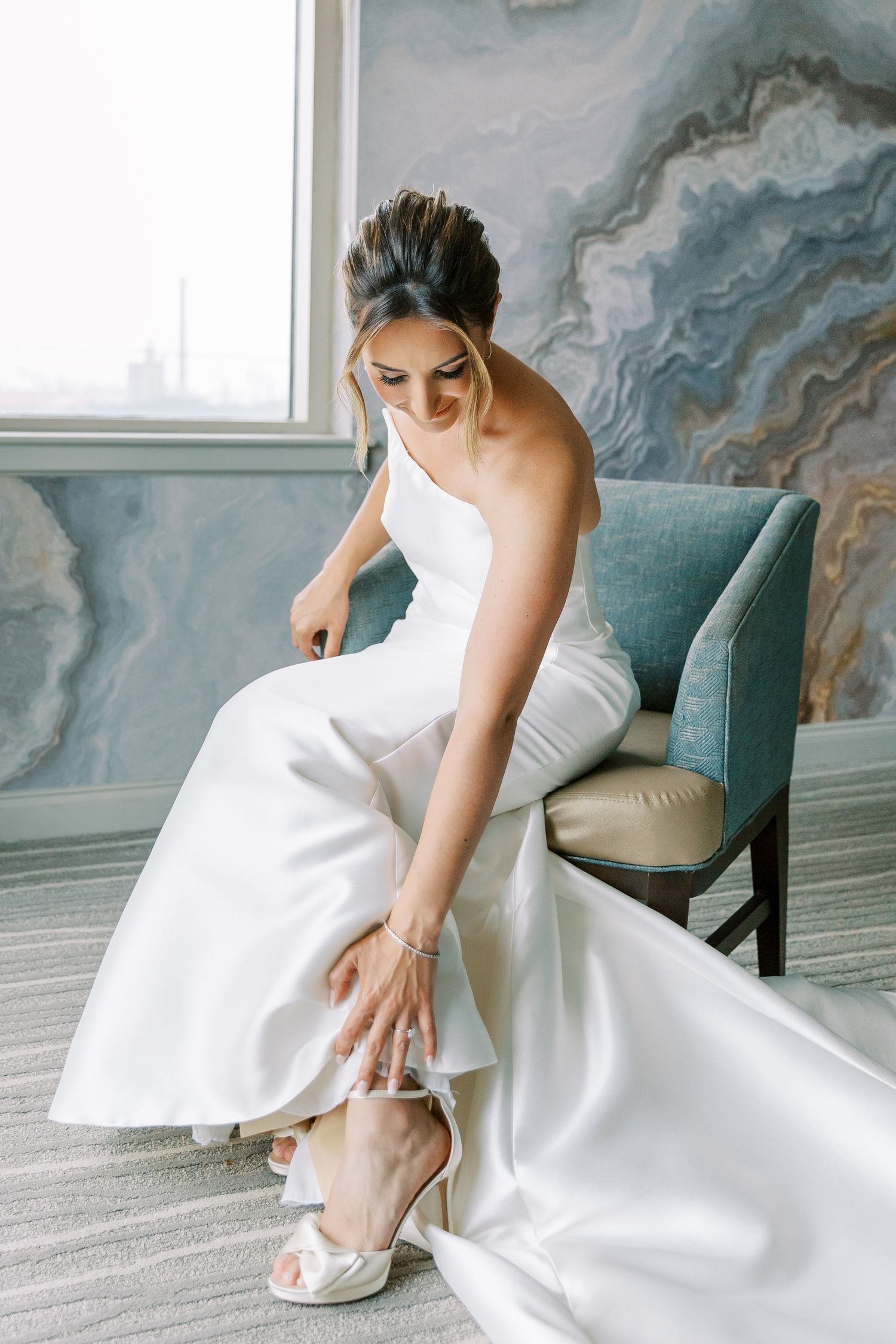A white bridal gown photographed against a marbled wall backdrop in an elegant setting.