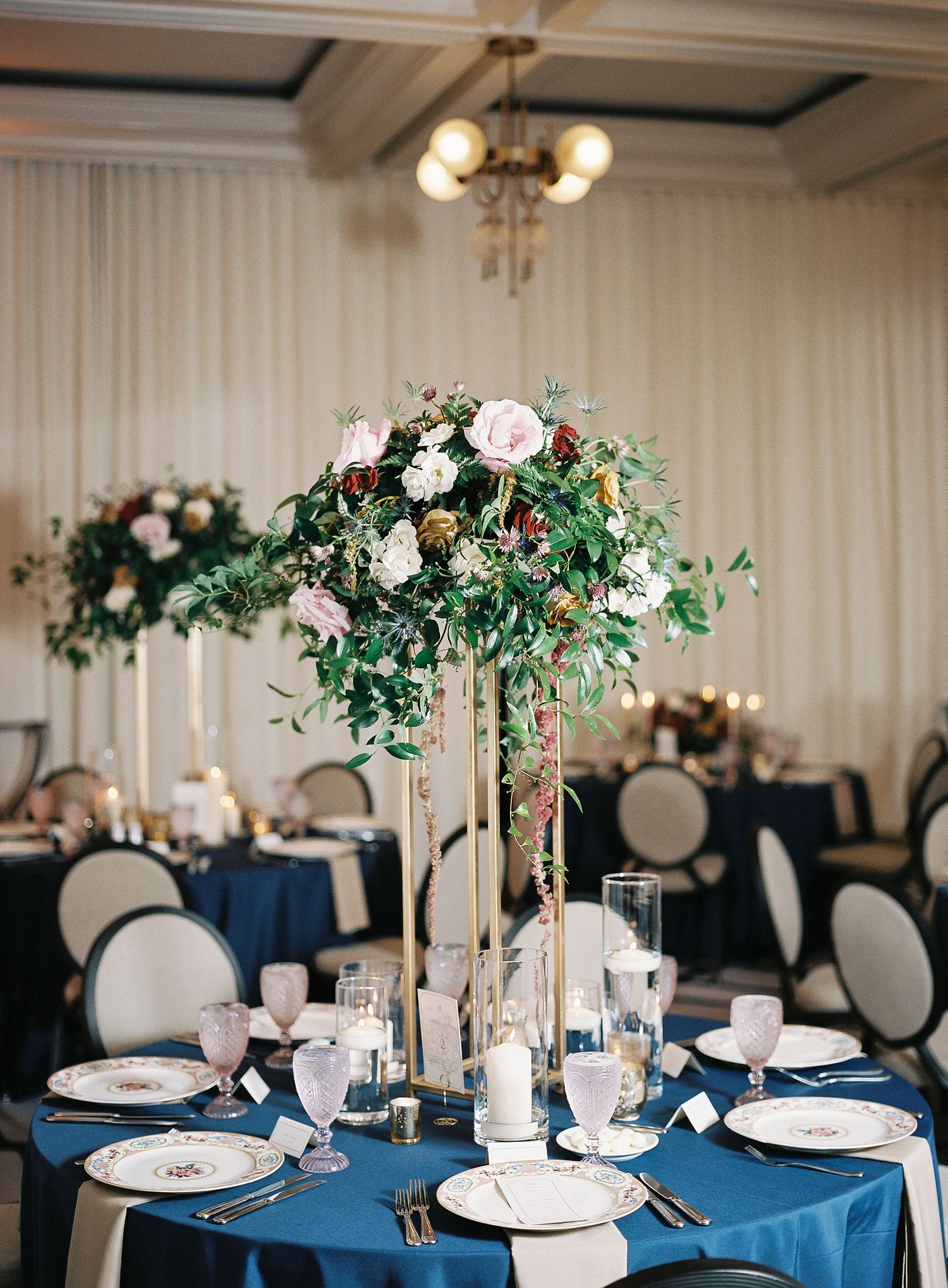 Tall floral centerpiece with white roses and greenery on navy blue tablecloth in an elegant reception setting at Perry Lane Hotel