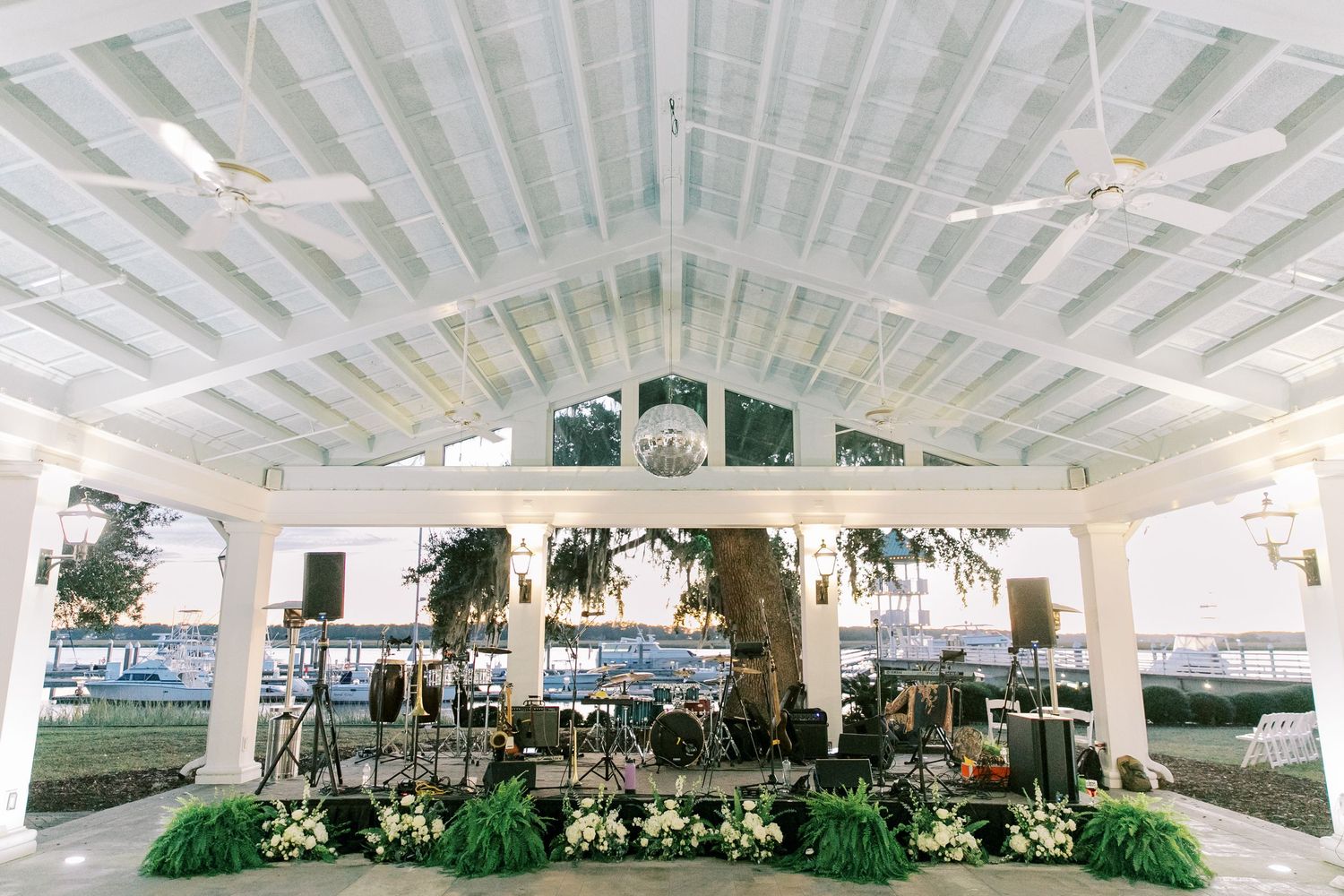 Elegant white reception pavilion with vaulted ceiling and hanging greenery decorations.