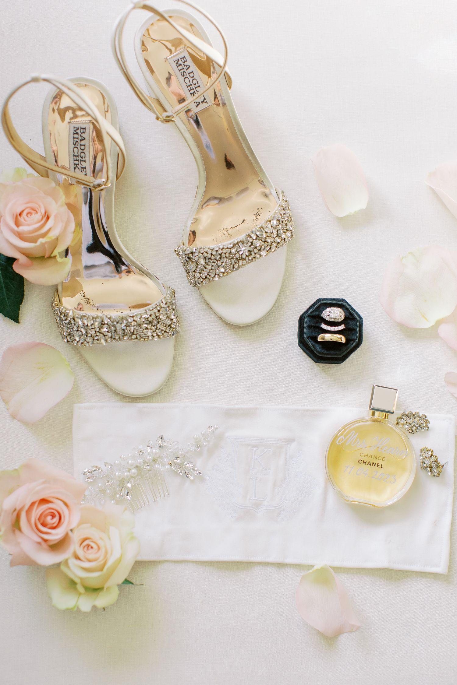 Wedding accessories including crystal sandals, roses, and perfume arranged on white background.