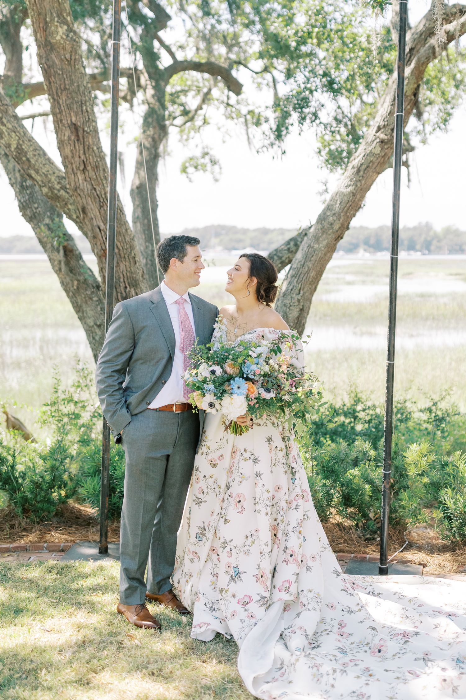 A romantic outdoor wedding portrait under moss-draped trees beside a marsh.