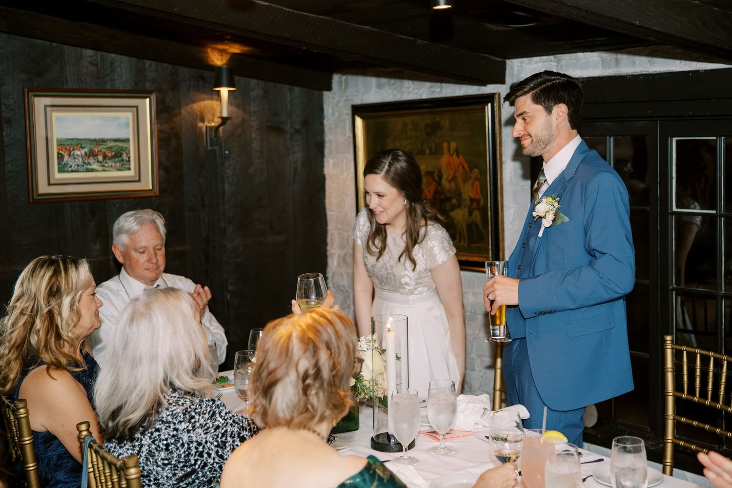 Wedding reception celebration in a dark wood-paneled room with elegant table settings.