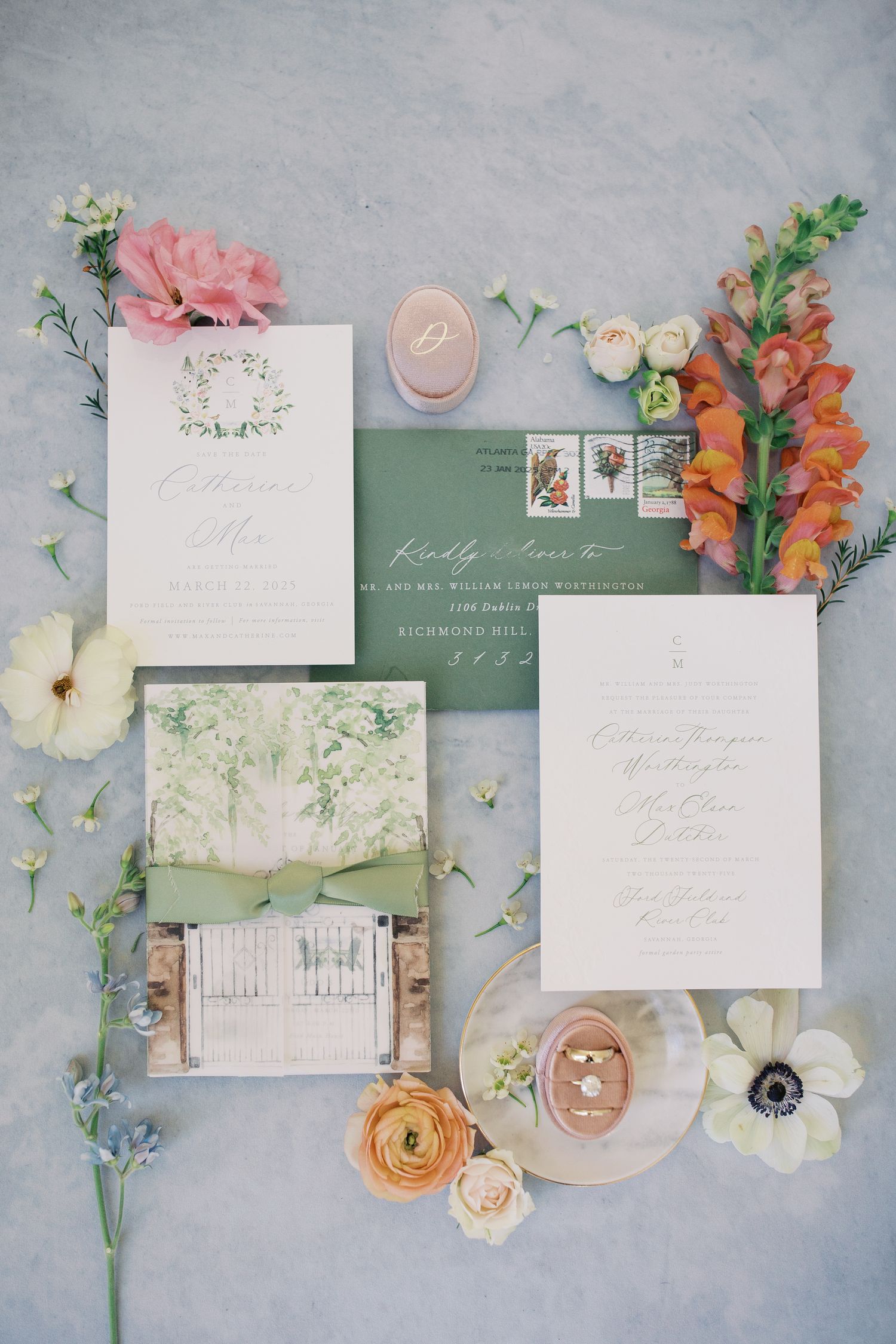 Elegant wedding invitation suite with floral elements in coral and sage green laid out on a light gray textured background.