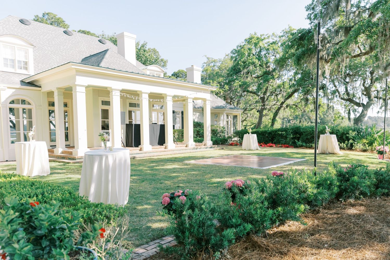Exterior view of a white colonial-style building with columns and landscaped gardens.