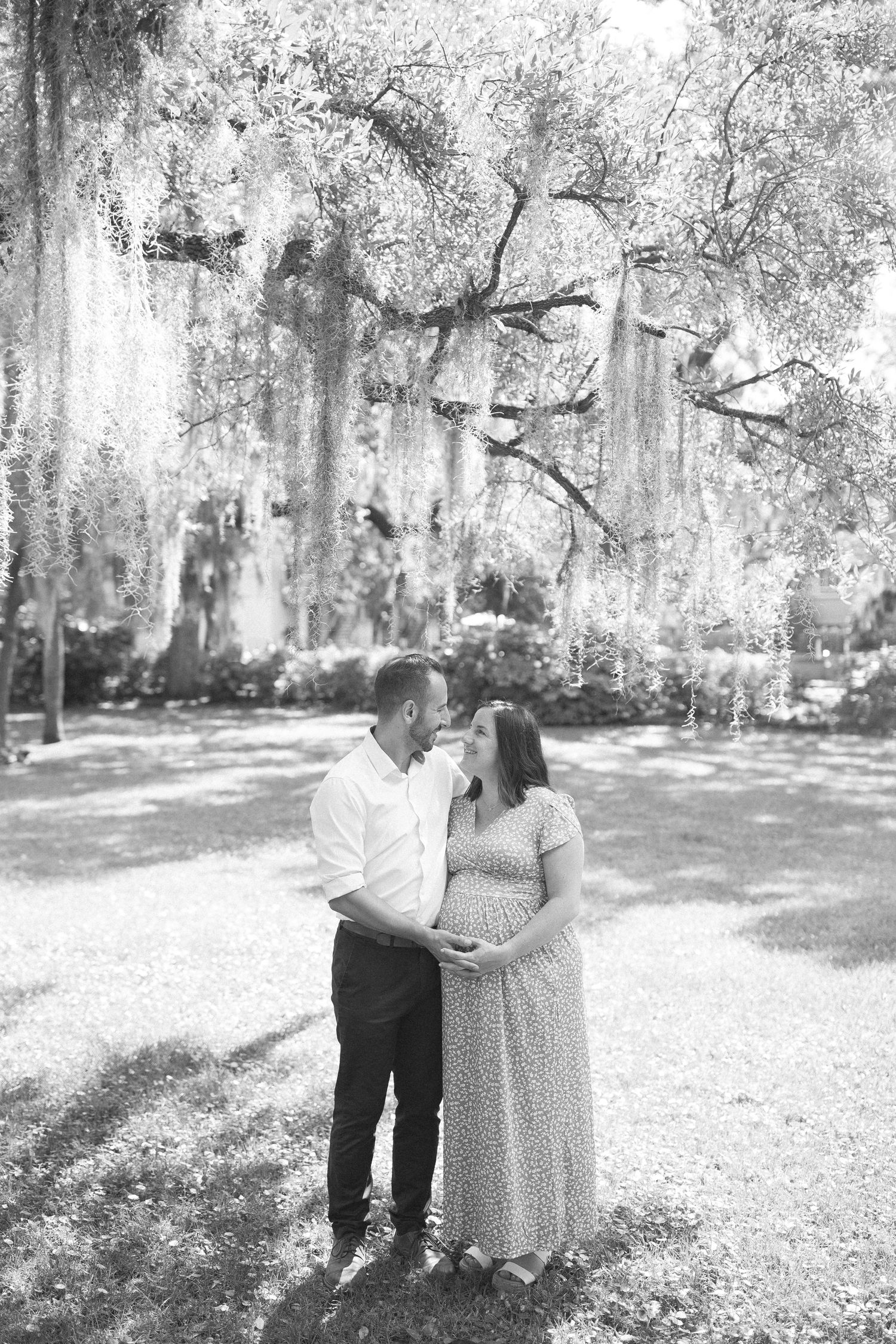 Black and white photos of a couple having an intimate moment under moss-draped trees.