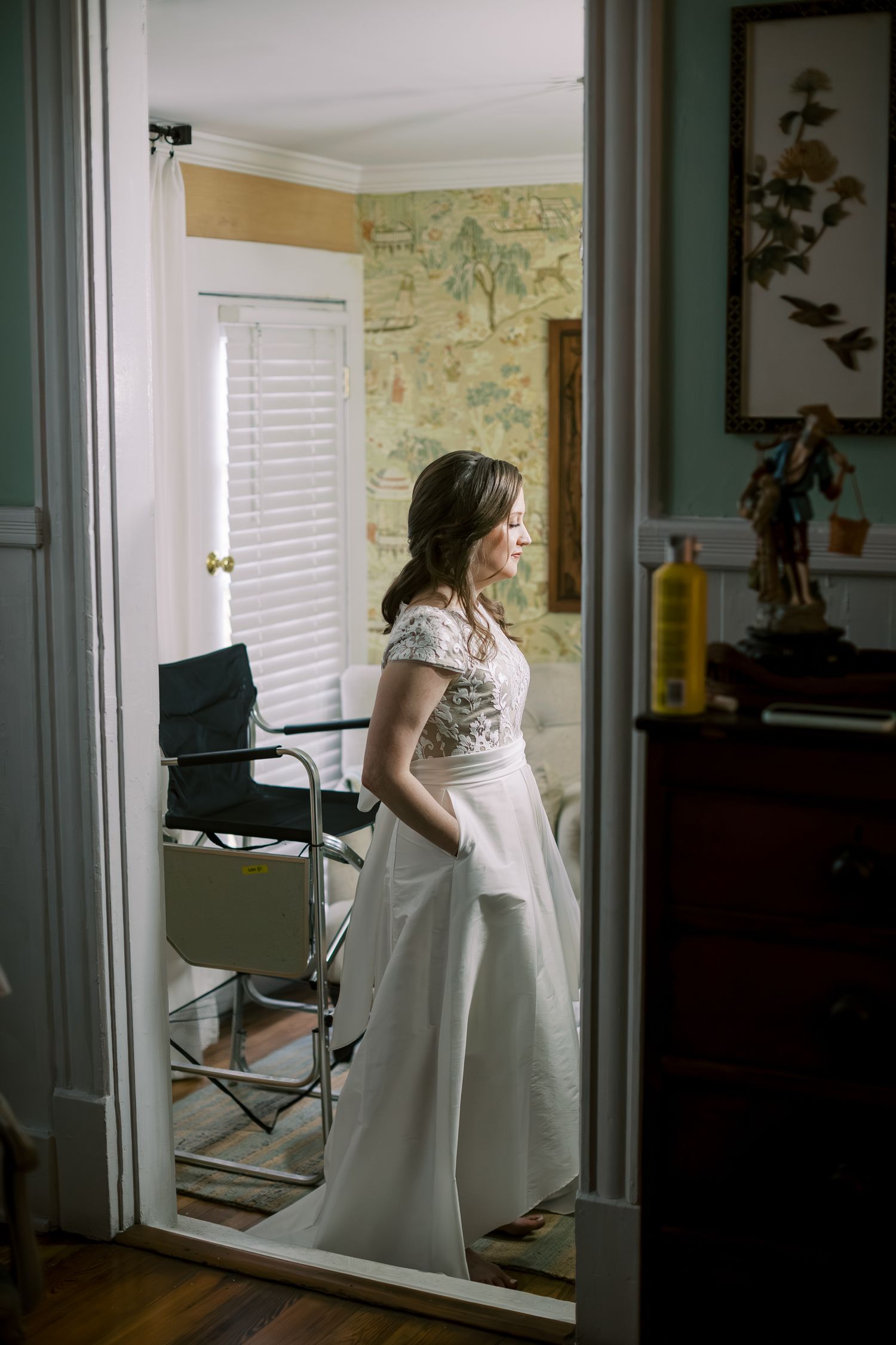A quiet moment captured in a room with vintage wallpaper and natural light streaming in.