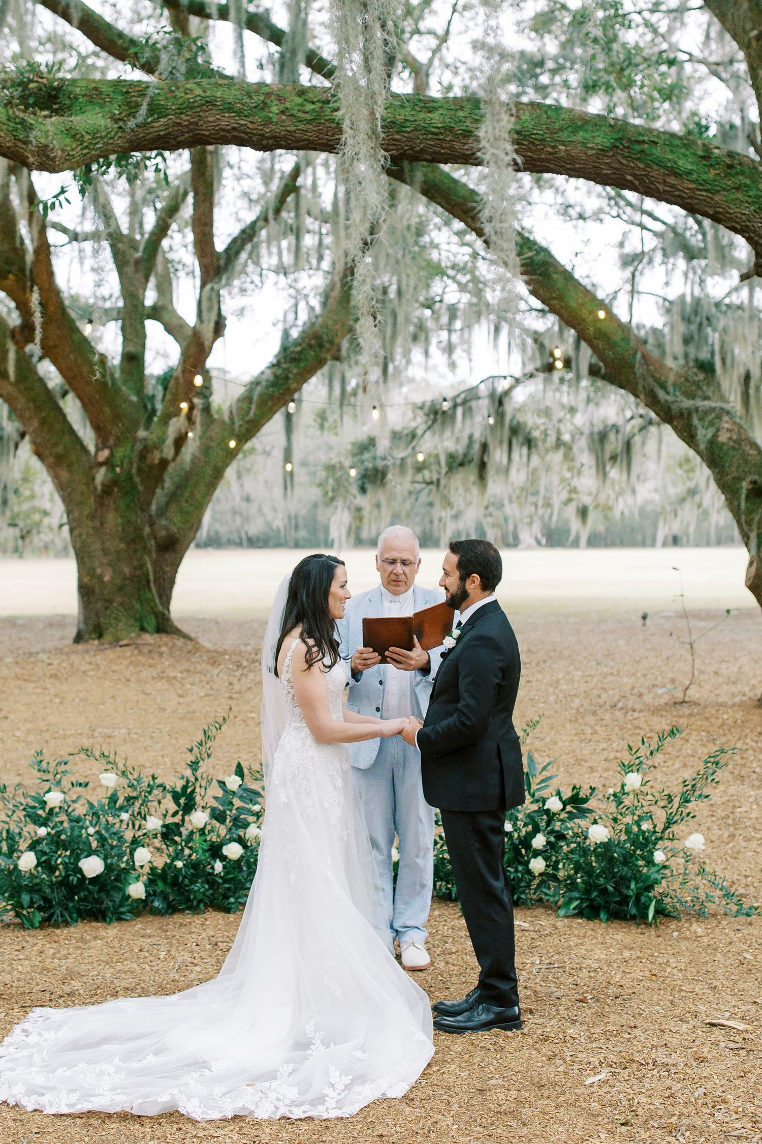 Wedding ceremony under Spanish moss-draped oak trees in Southern garden setting at Hewitt Oaks in Bluffton.