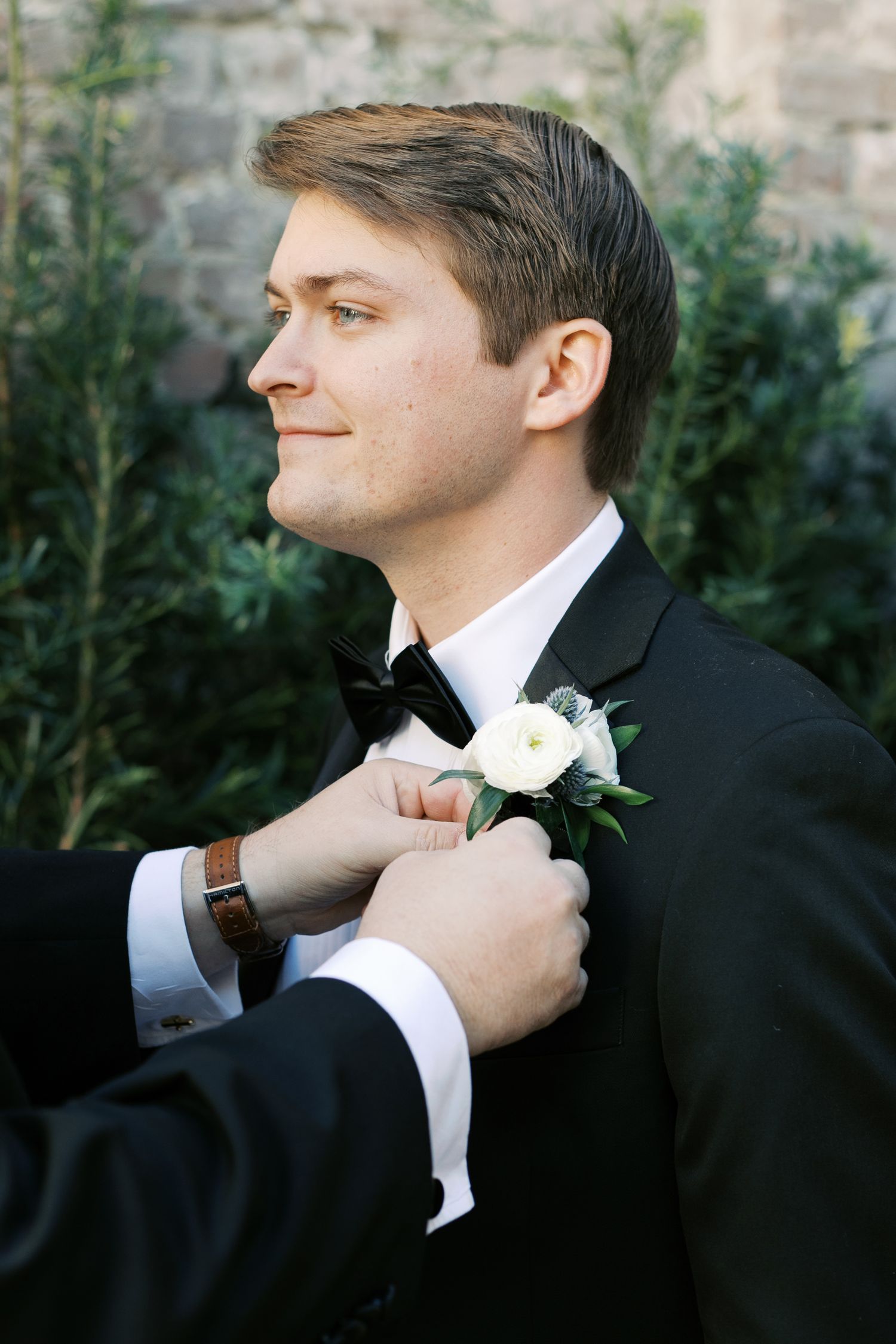 Multiple shots of a groom getting ready, adjusting his boutonniere and formal attire.